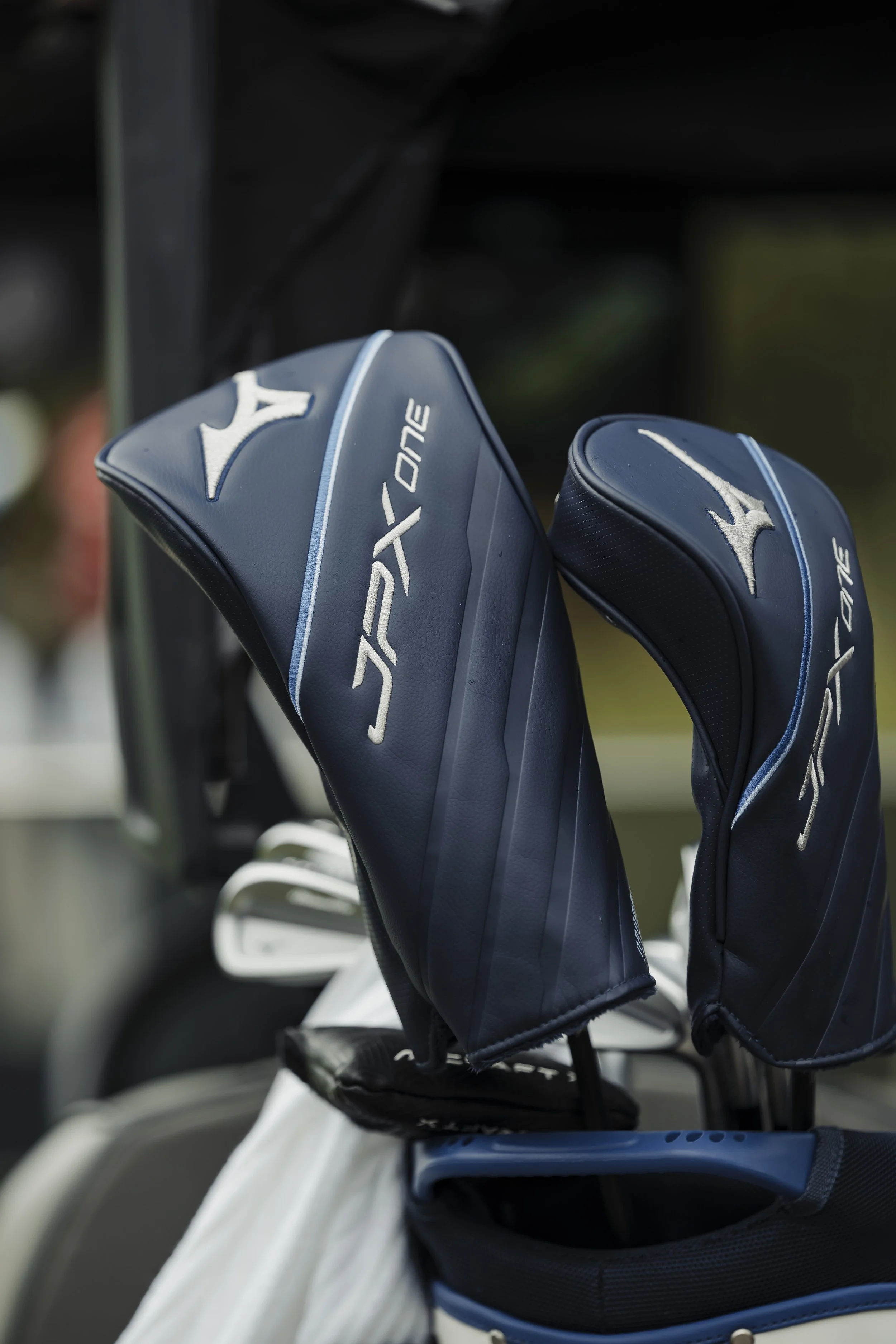 Golf club head covers with blue and white color, branded with Mizuno and the logo, on a golf bag.