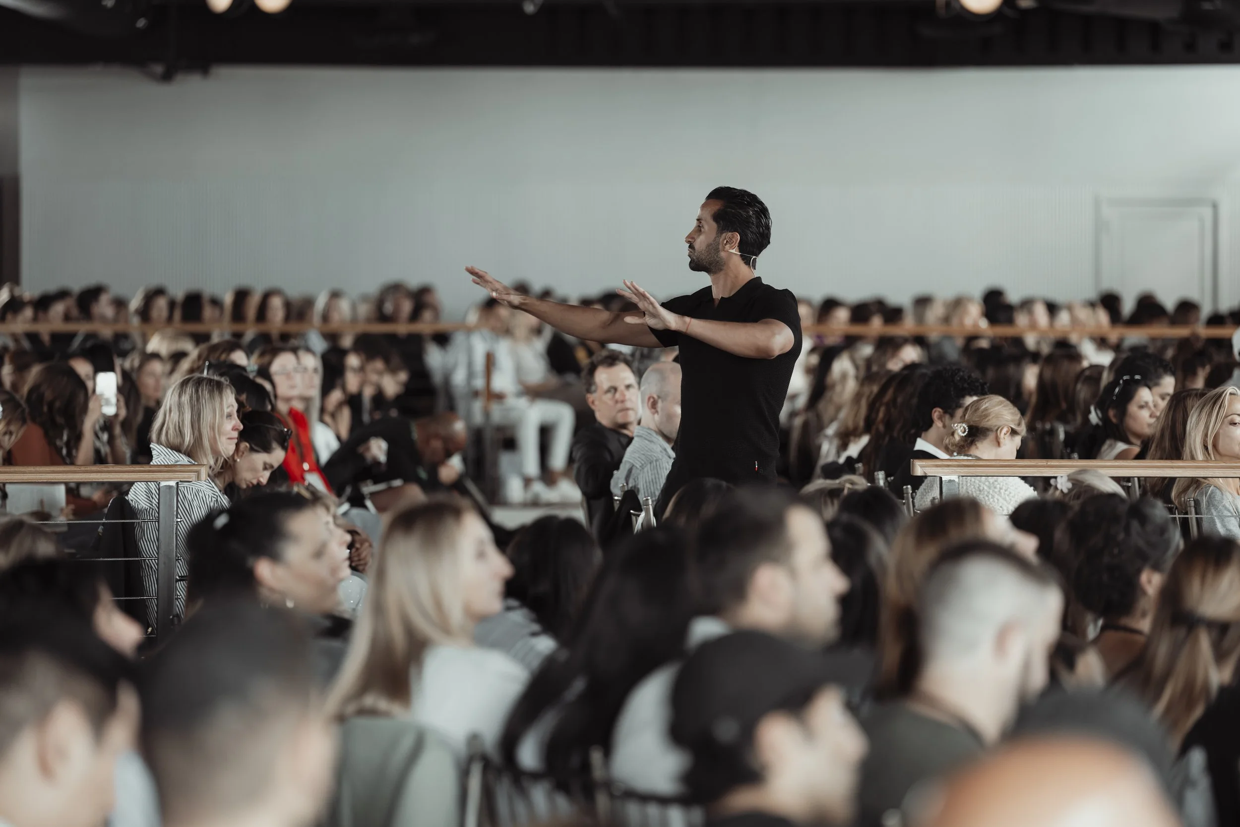 A speaker or presenter standing on stage in front of a large audience at a conference or seminar.