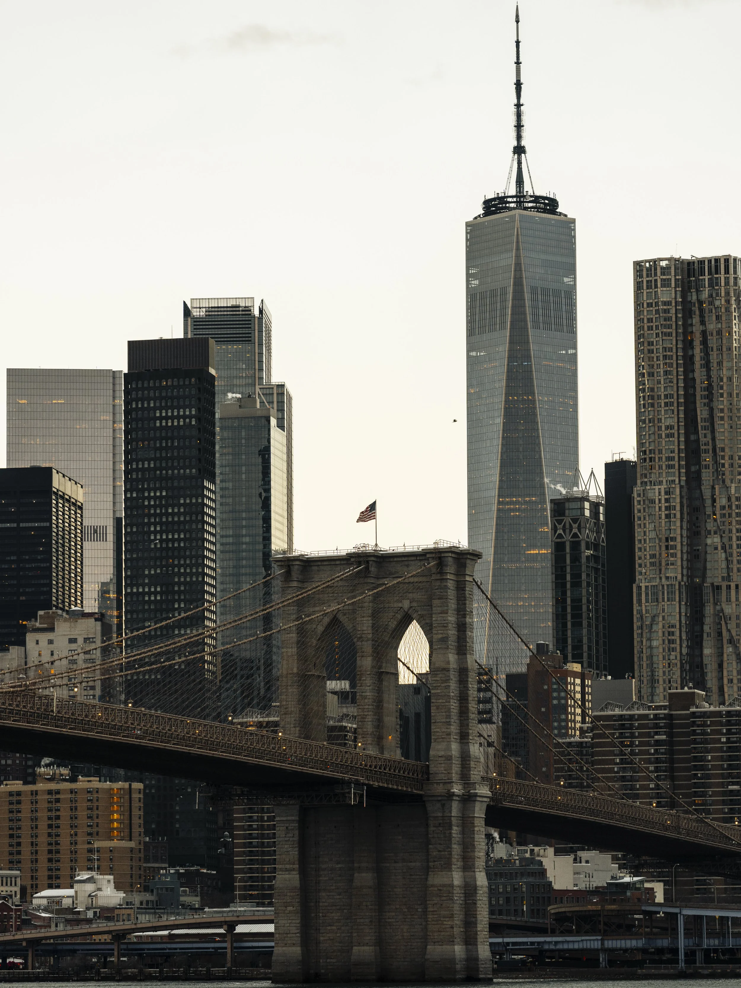 View of the Brooklyn Bridge with the Manhattan skyline and One World Trade Center in New York City during daylight.