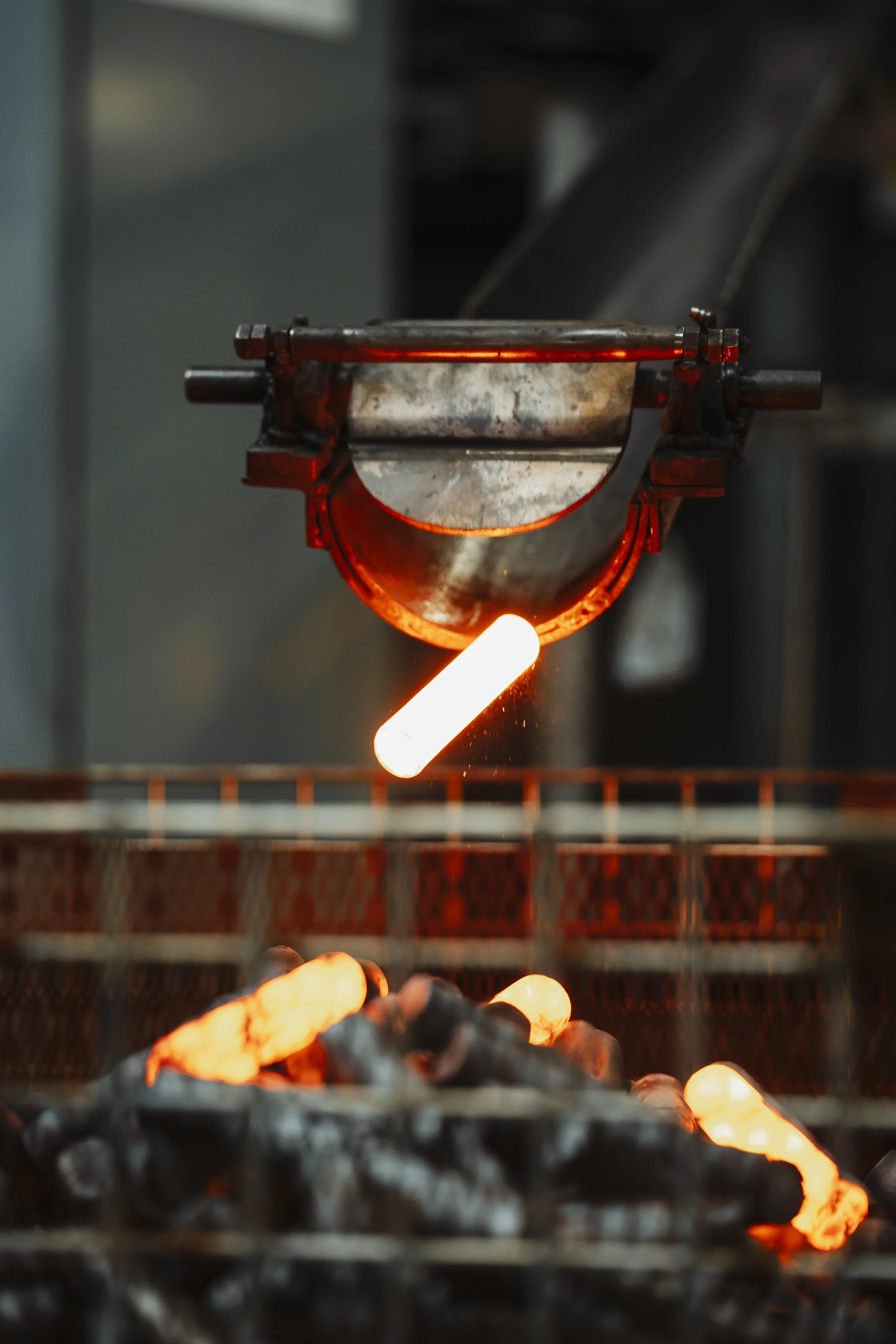 Metalologist pouring molten metal from a ladle into molds in foundry