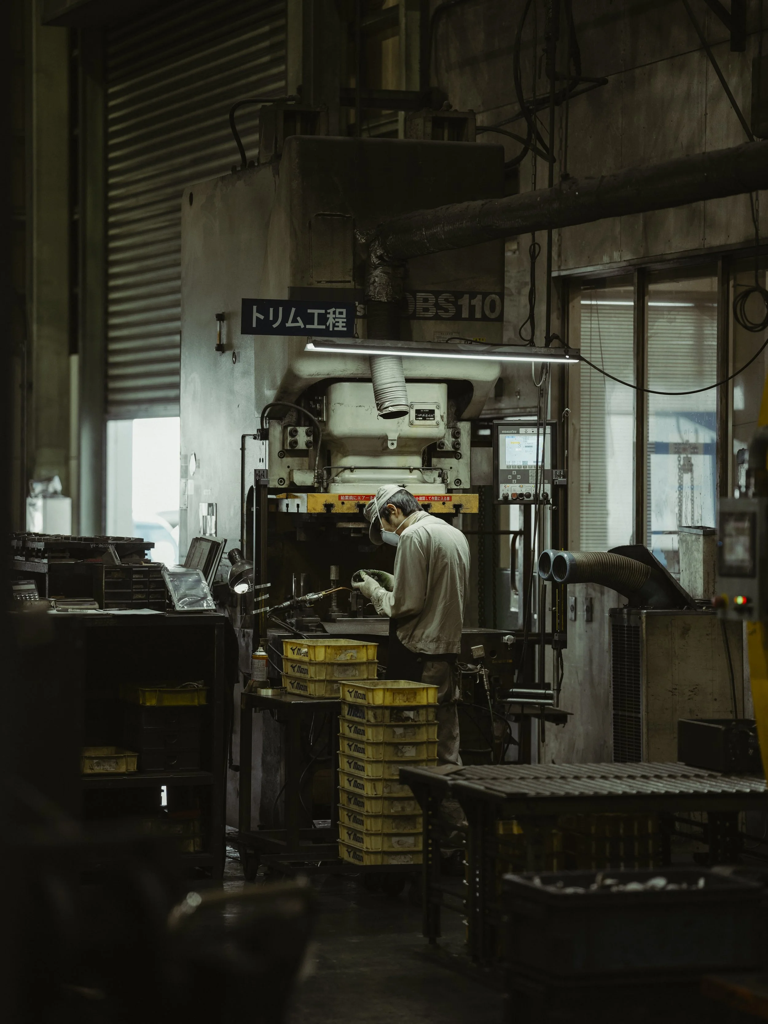 A worker wearing protective gear operating machinery in an industrial workshop.