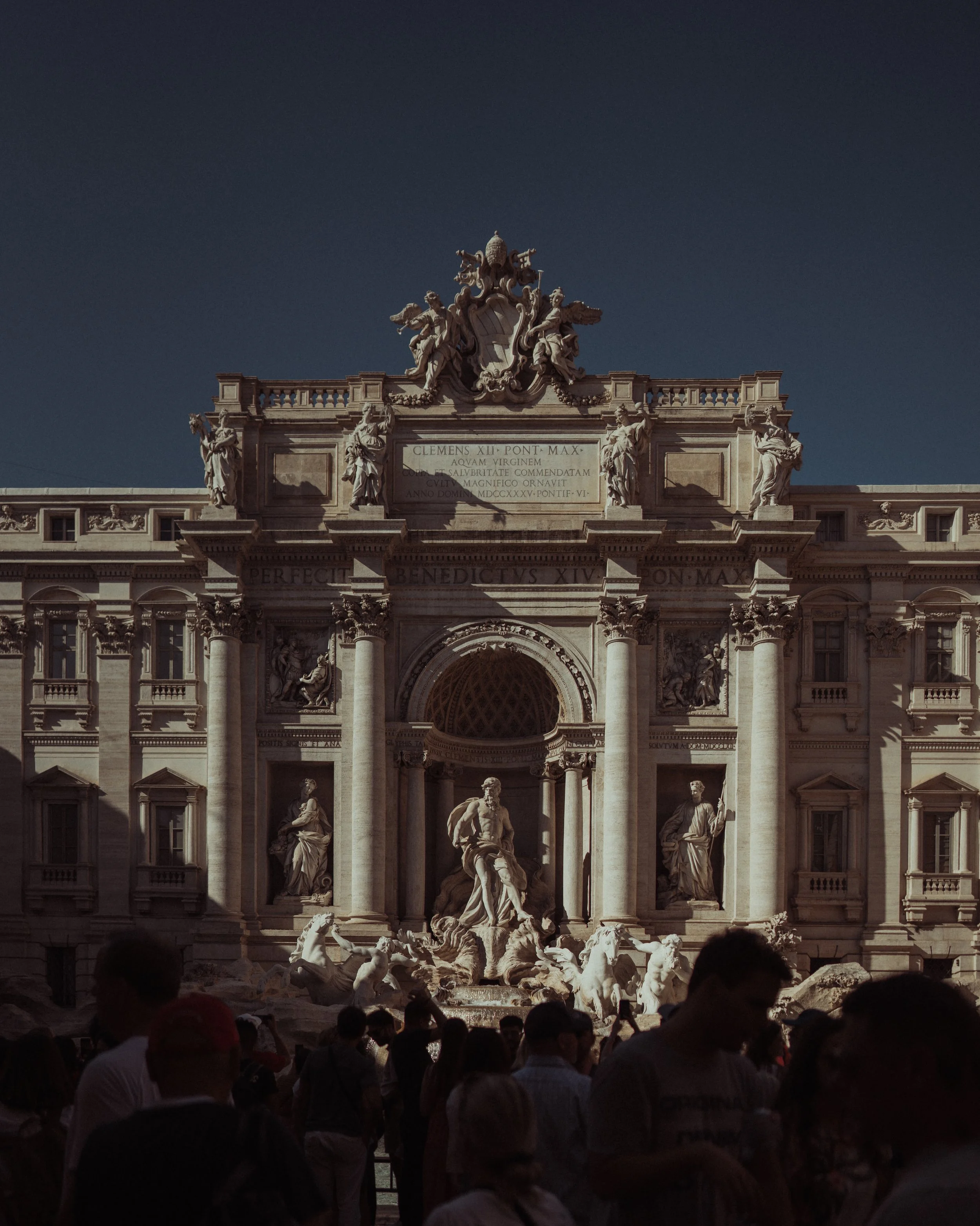 The Trevi Fountain in Rome, Italy, with Baroque architecture, statues, and a crowd of tourists in the foreground.