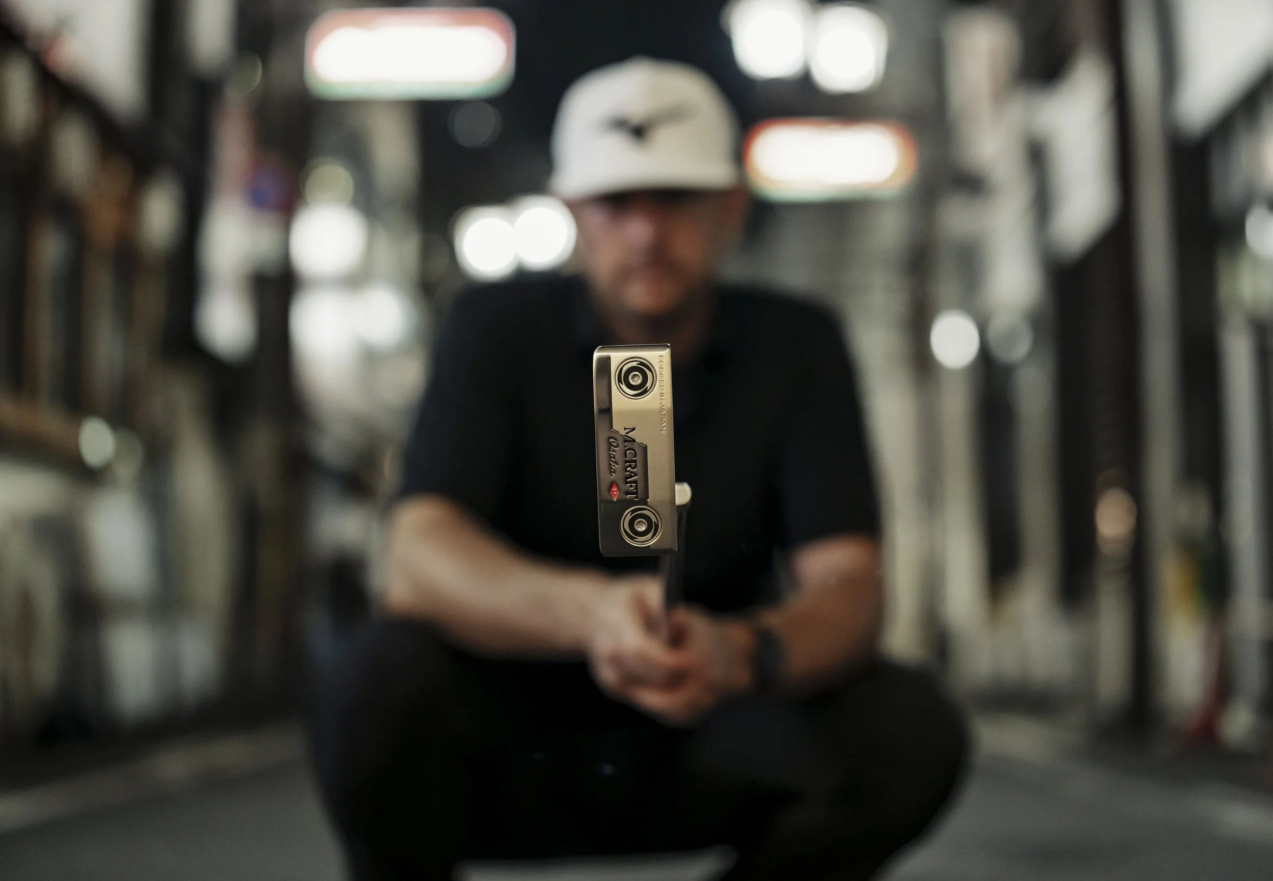 A person sitting inside a room, holding a metal object with two targets on it, with the focus on the object and a blurred background.