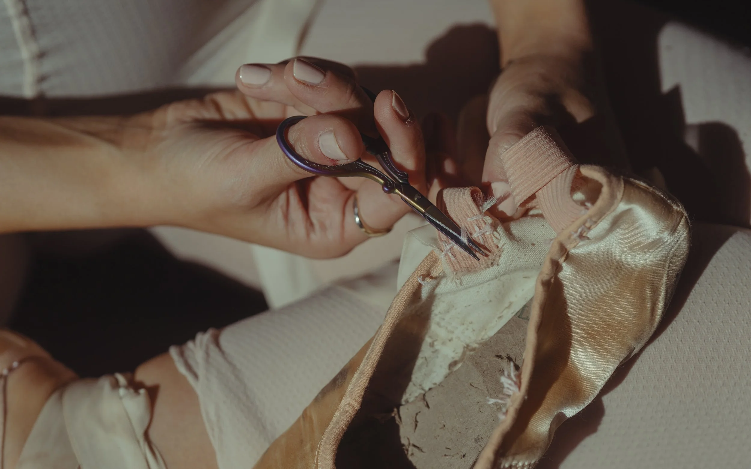 Person using small scissors to cut a fabric label sewn onto a garment.