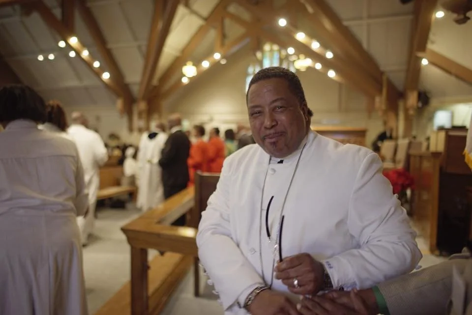 Pastor Booker in white attire inside the church