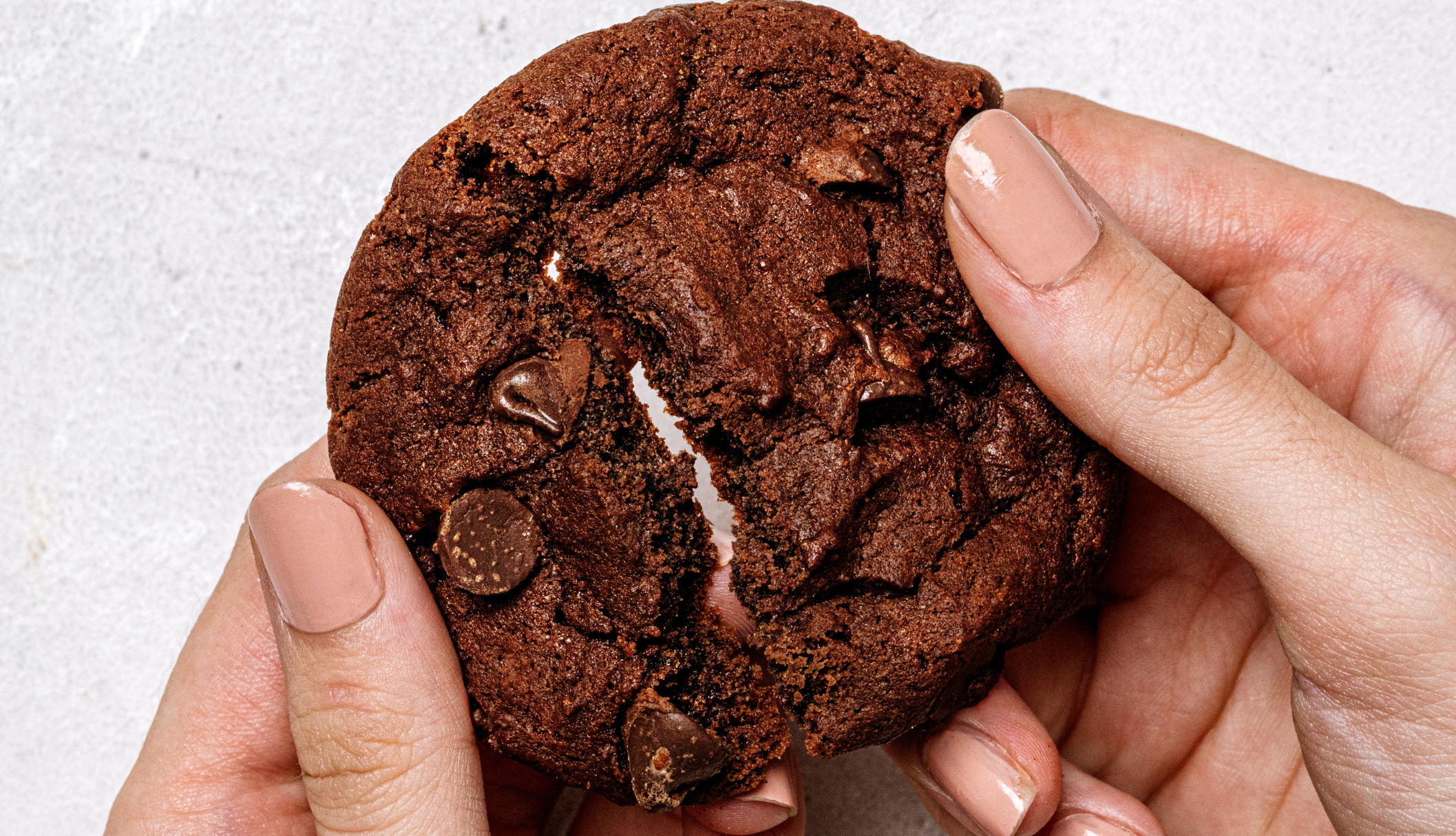 person holding a chocolate biscuit, an example of sensory hunger triggered by the sight of food