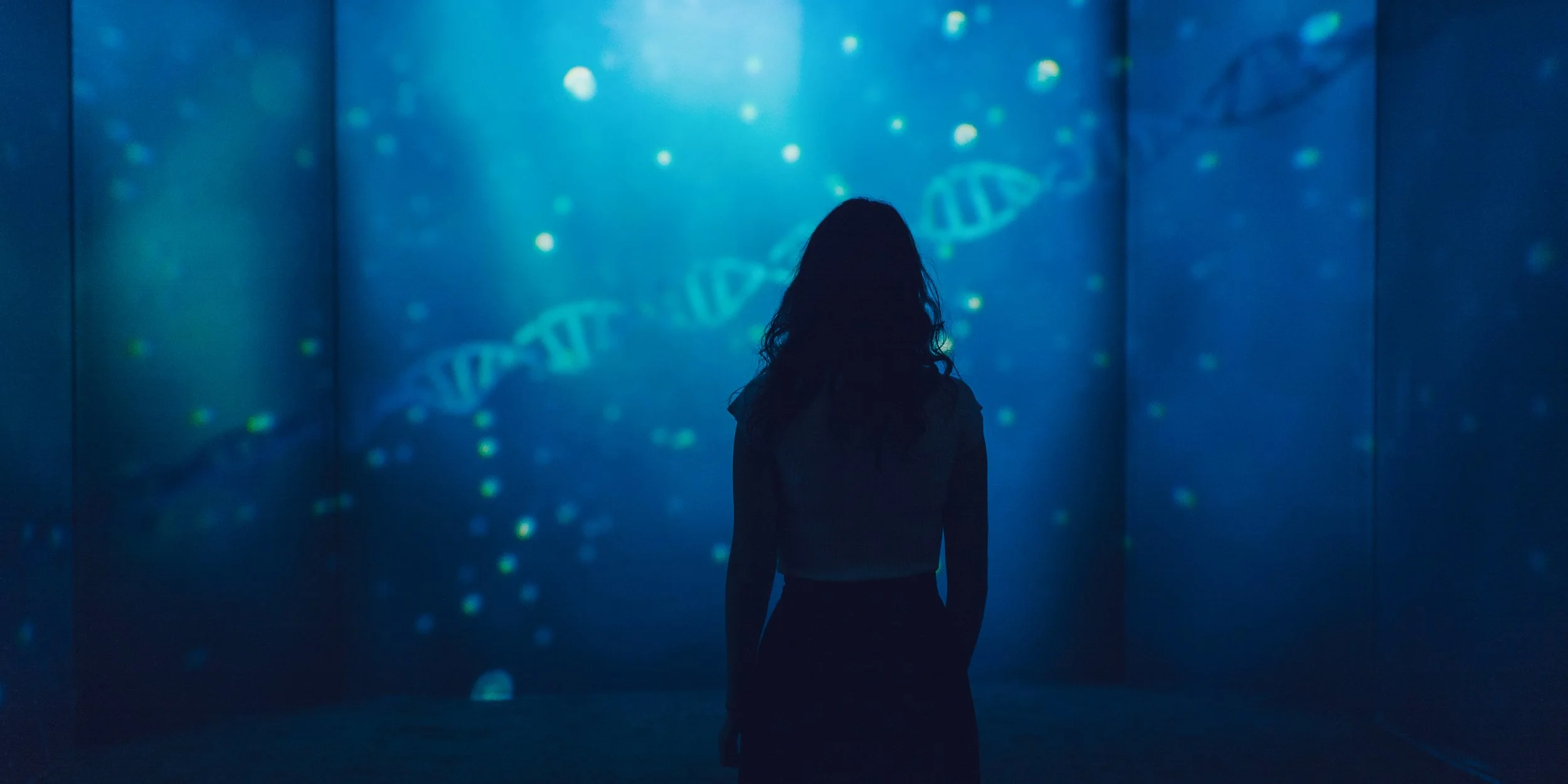 A visitor gazing at projection mapping showcasing hypothetical molecular DNA modification
