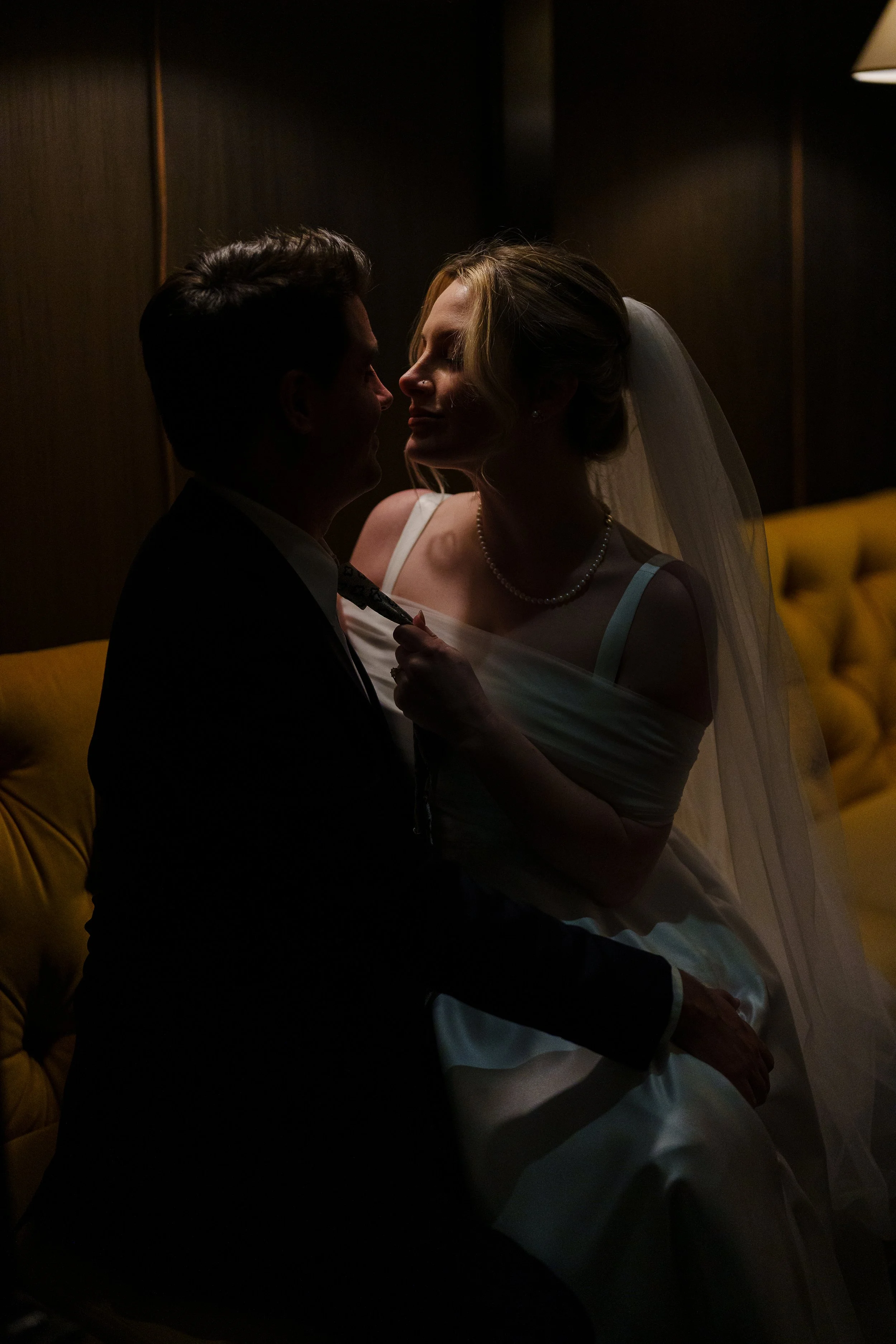 Bride and groom romantic embrace is moody lighting for couples photos in Rittenhouse Hotel in Philadelphia, PA. 