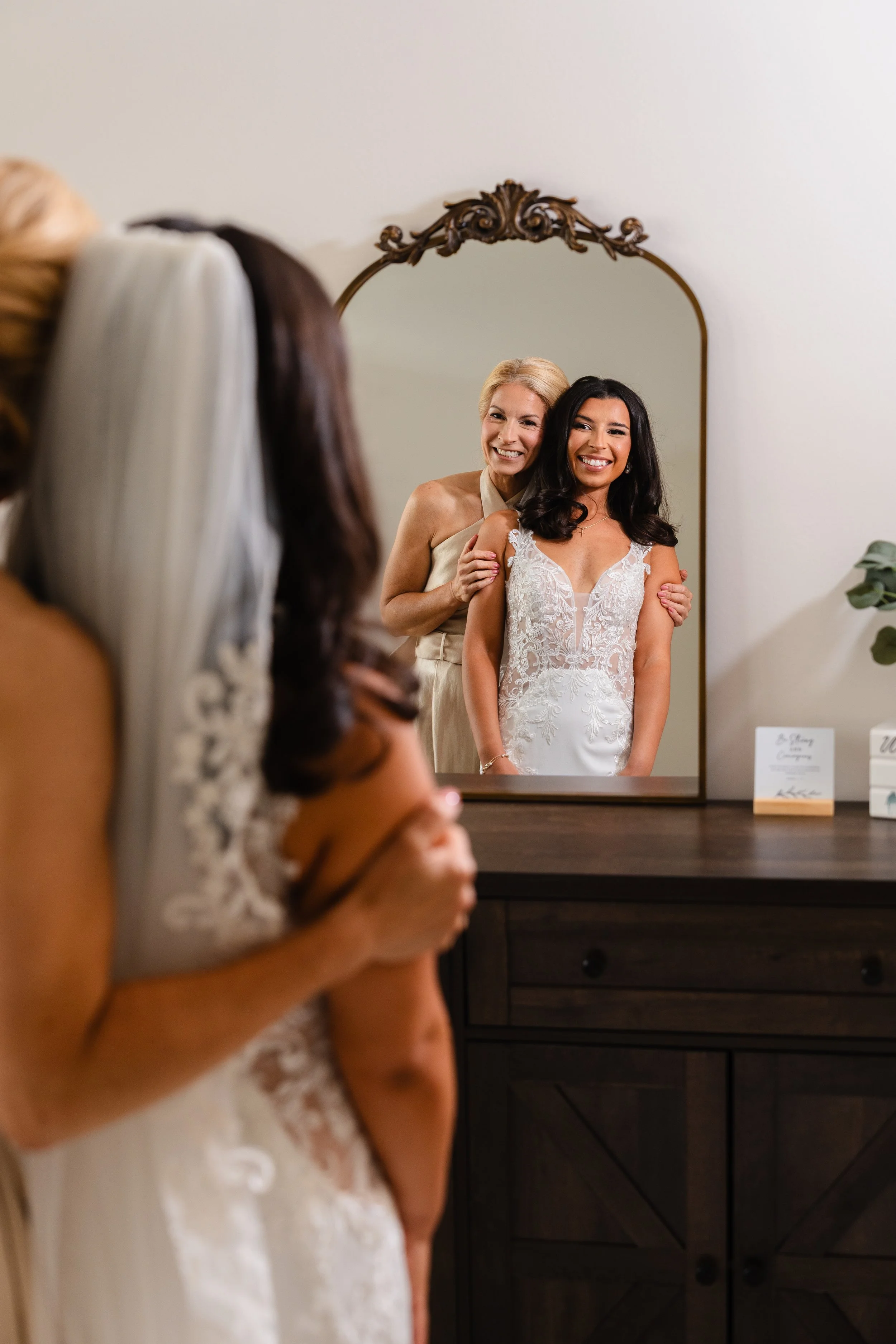 Bride with mom happily embracing in mirror during getting ready photos at South Jersey home. 