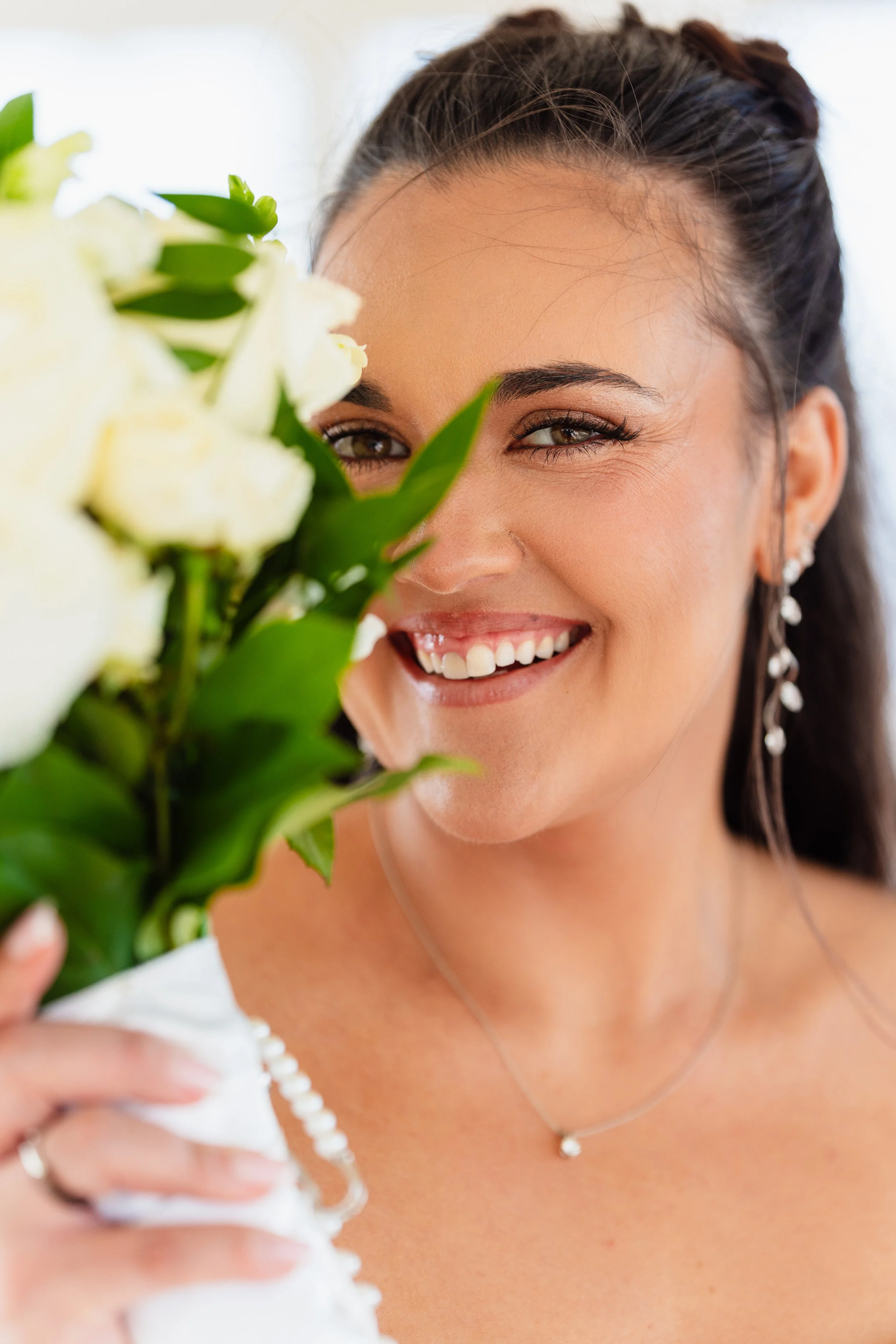Bride smiling behind her bouquet on Ocean Gate Beach in Ocean Gate, New Jersey. 