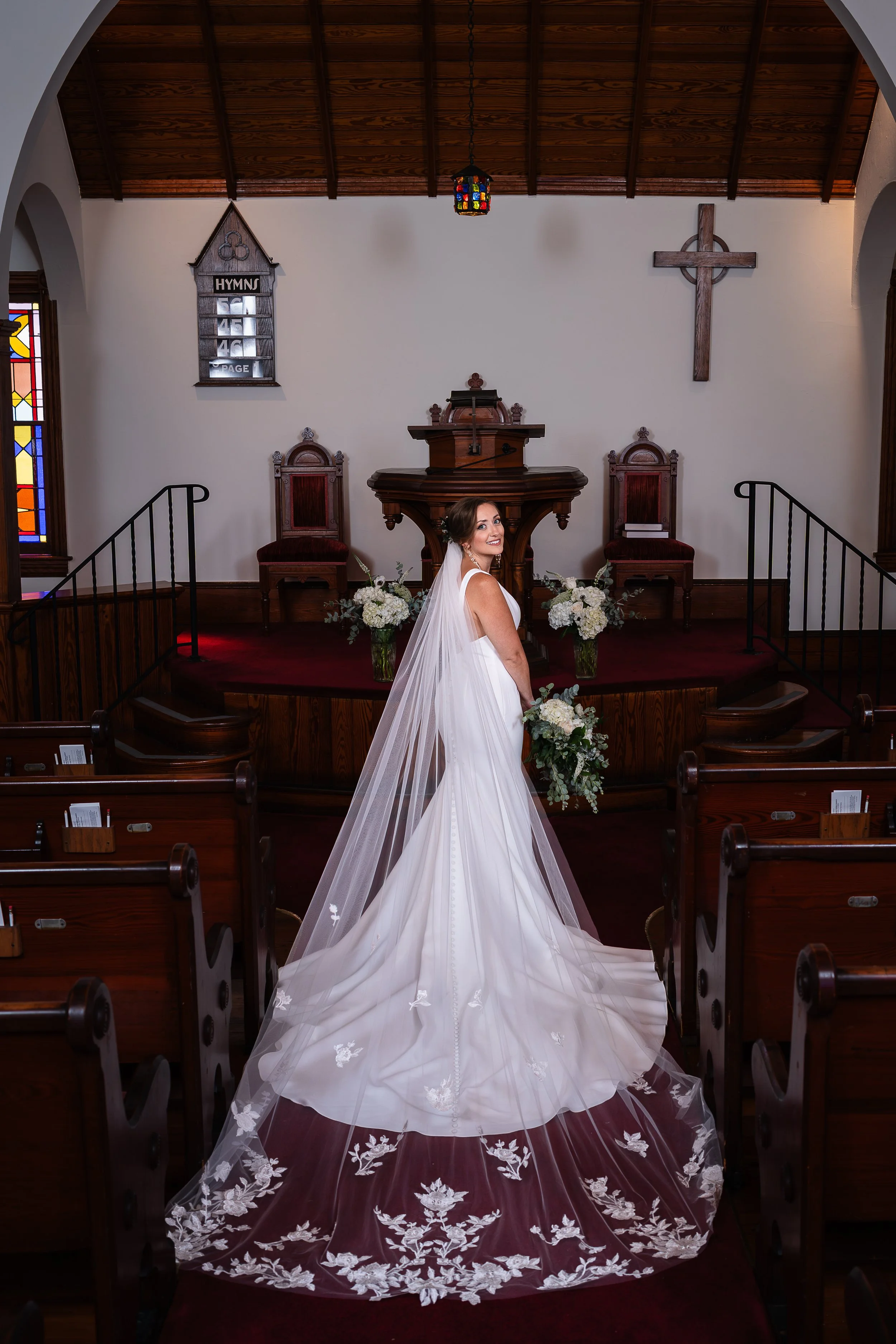 Bride posing looking back over shoulder for bridal portrait in Wells Memorial Presbyterian Church in Avalon, New Jersey. 