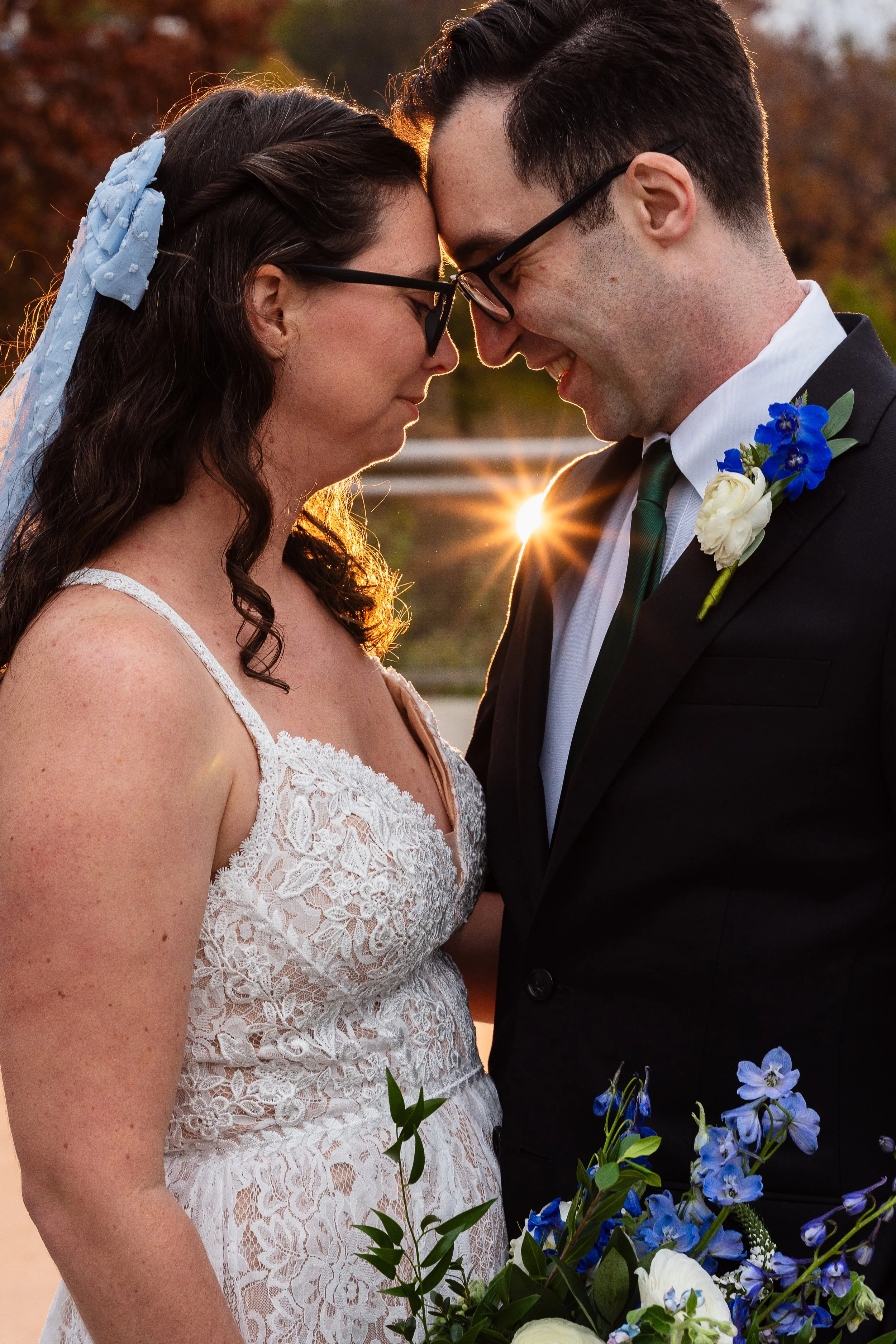 Bride and Groom touching foreheads for couples portraits with a starburst over grooms shoulder in Schuylkill River Park in Philadelphia, PA. 
