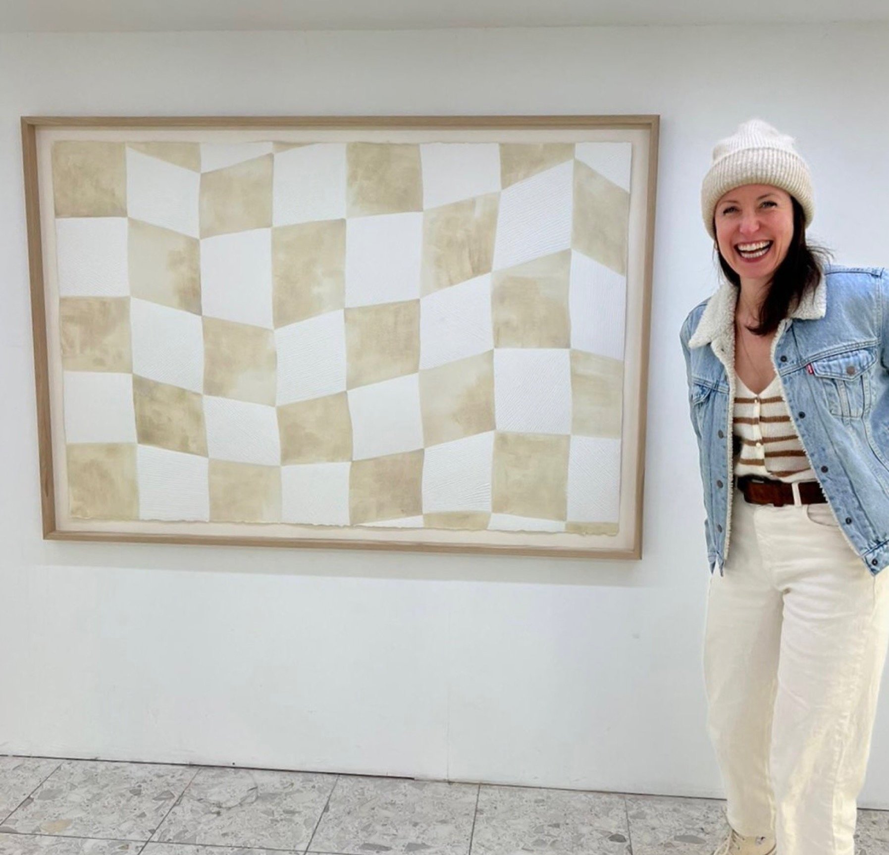 artist mimi zouch standing next to her large carved checkerboard artwork