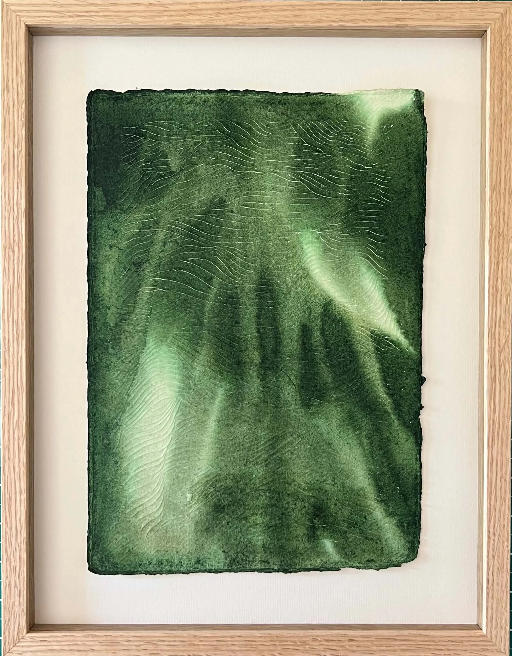 textural green painting on white paper with carvings