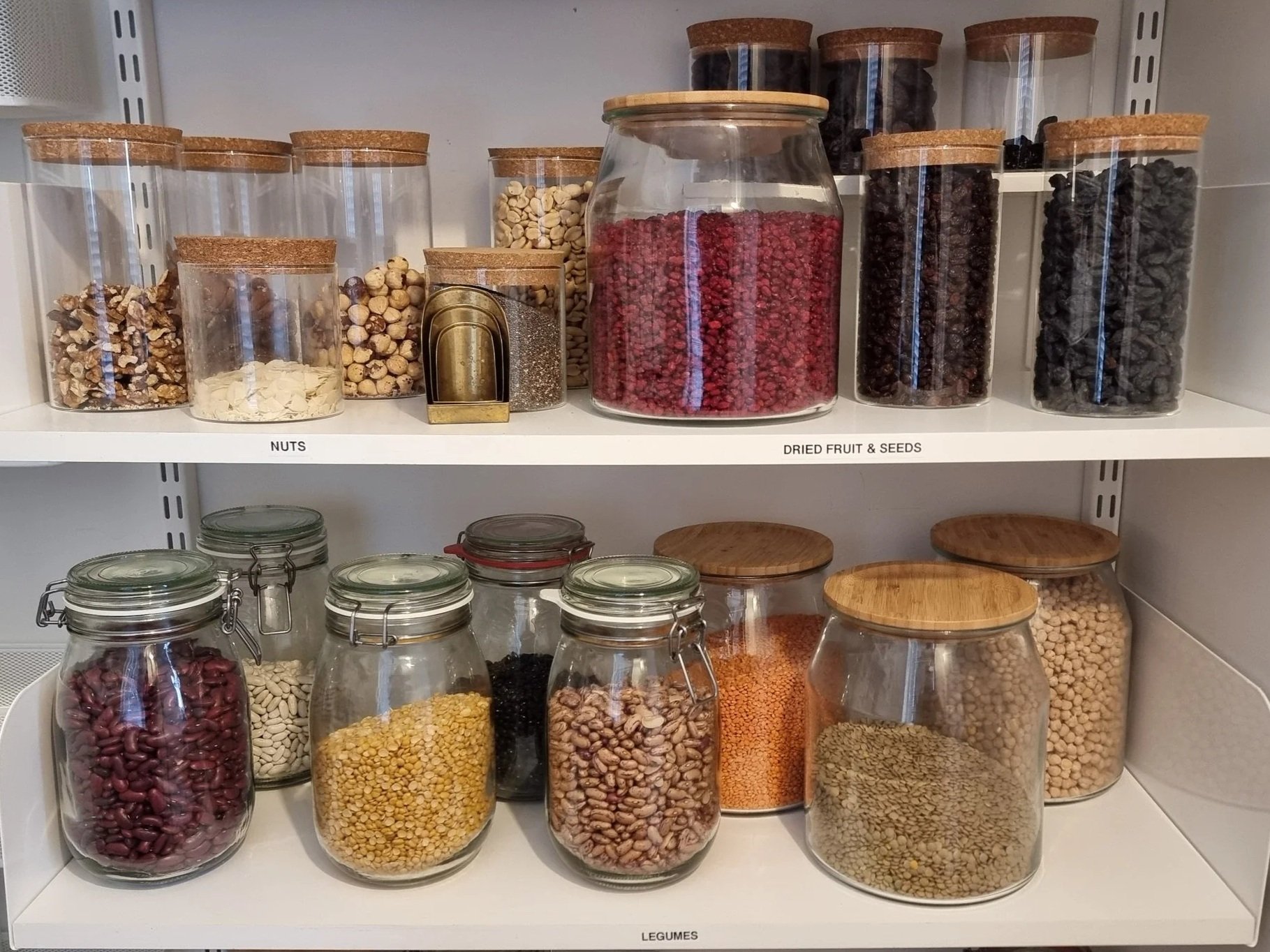 Organized pantry shelves with legumes , nuts and dried fruit in organized jars