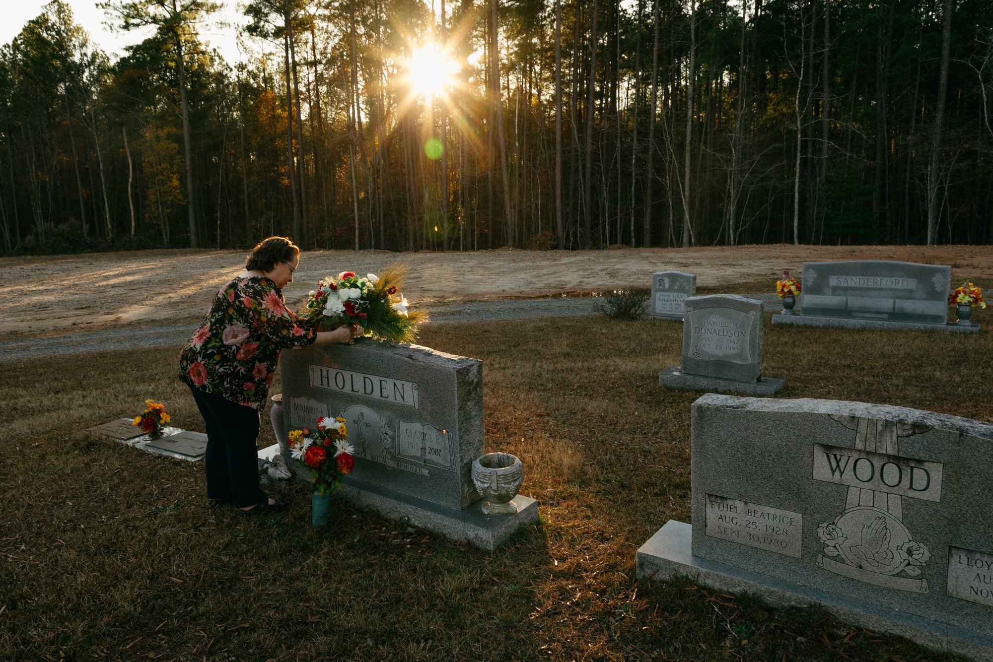 Sharron Bouqin places a bouquet of flowers on her grandparents' gravestone at Merry Oaks Cemetery in Chatham County, N.C. on Nov. 29, 2022. Sharron is the third generation of her family to call Merry Oaks home, a place she's seen gradually lost to th