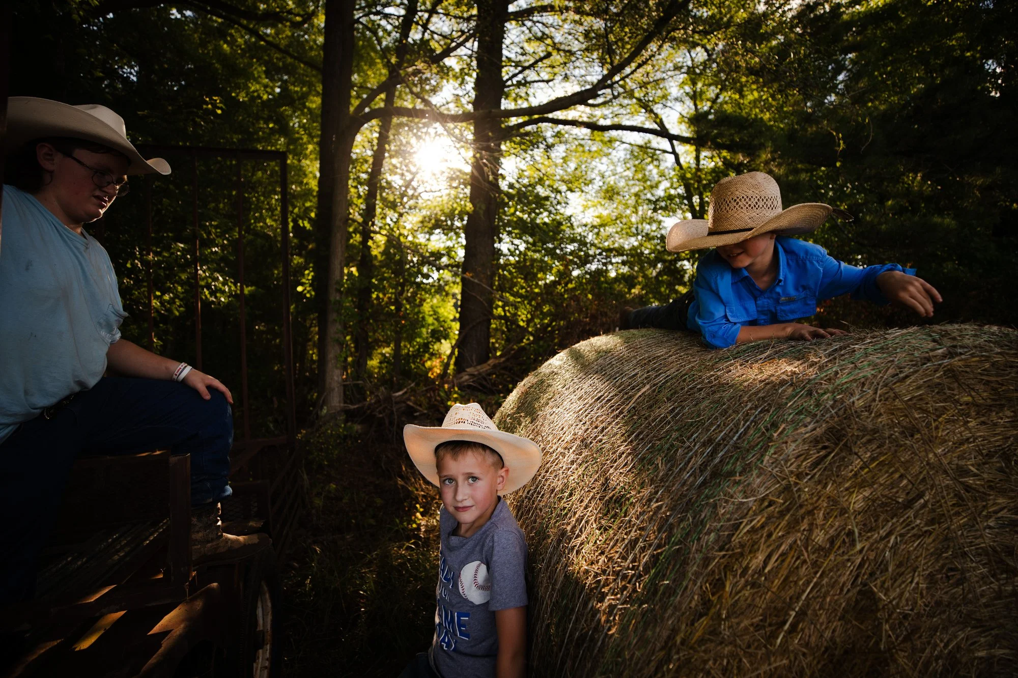 Colton, 8, plays on a hay bale with his friends Zach, 11, and Houston, 9, before the Silk Hope Pro Rodeo in Silk Hope, N.C. on Saturday, June 24, 2023.