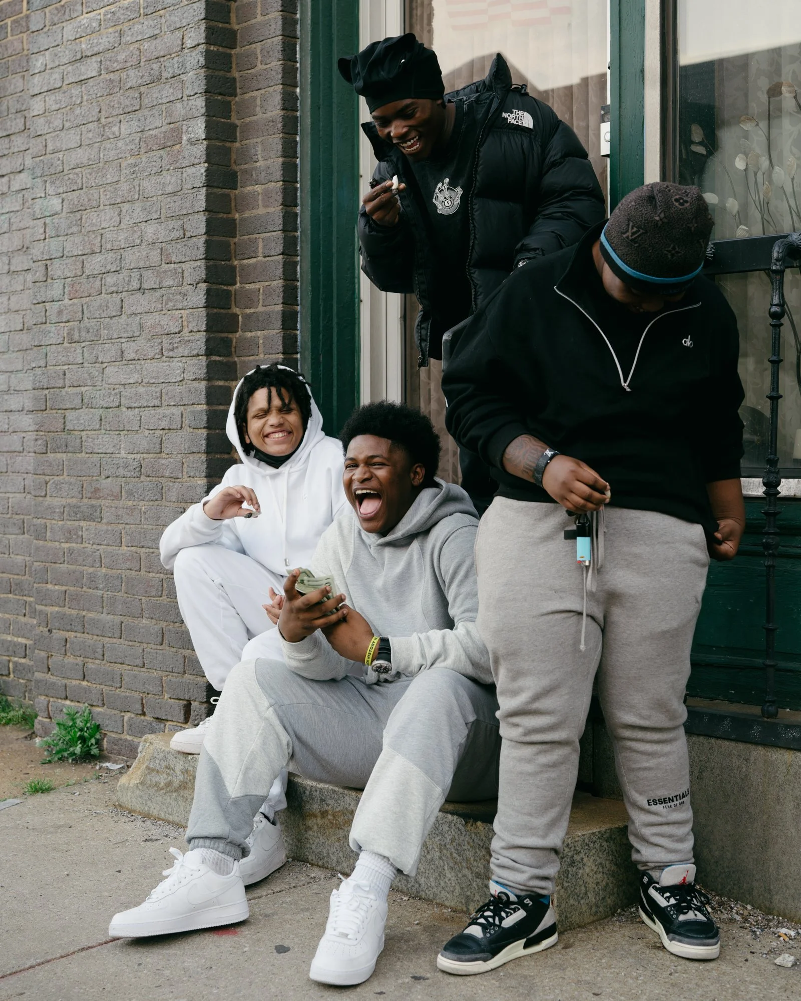 Larry, center, and his friends share a laugh on a stoop in Baltimore, Md. in 2026.
