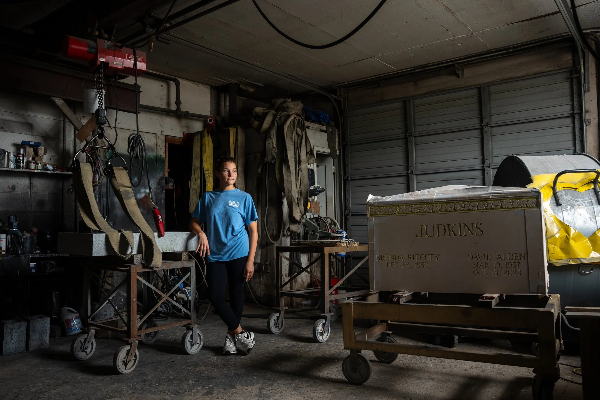Haley McNew, secretary at Whitener Monument in Kennett, Mo., poses for a portrait inside the workshop where headstones are engraved on September 23, 2024. McNew's job often places her in a role much like a grief counselor, as she helps families decid