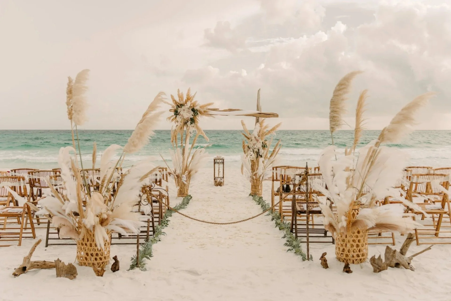 Luxury Florida beach wedding ceremony setup with pampas grass decor and oceanfront seating along the Emerald Coast.