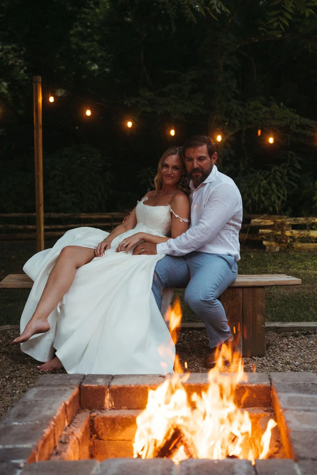 Romantic nighttime wedding photo at Leather Bound Hollow featuring a couple by the fire pit and café lights in East Tennessee.
