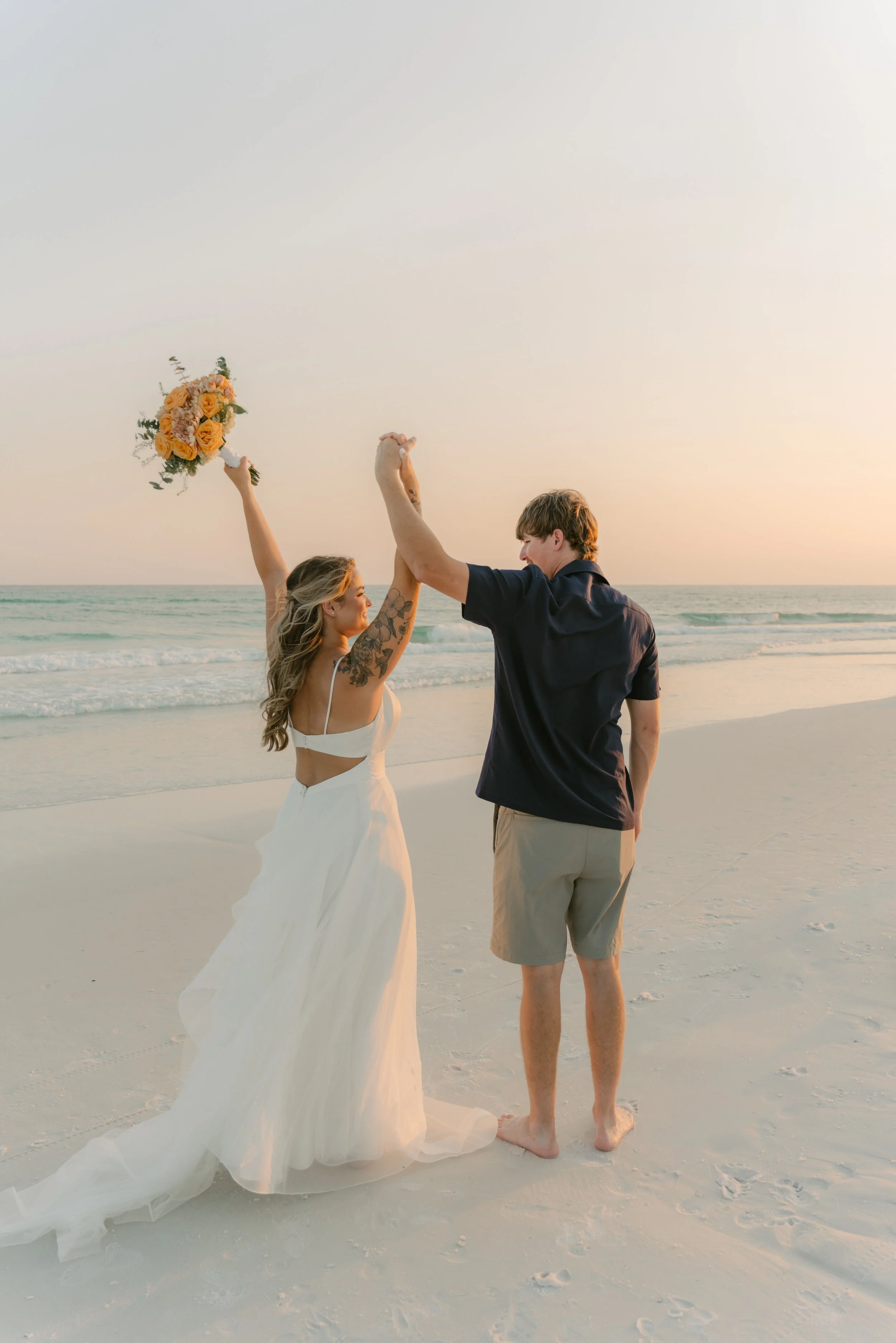 Couple walking along Panama City Beach after their destination wedding in Northwest Florida, photographed by Leather & Lace Wedding & Event Co.