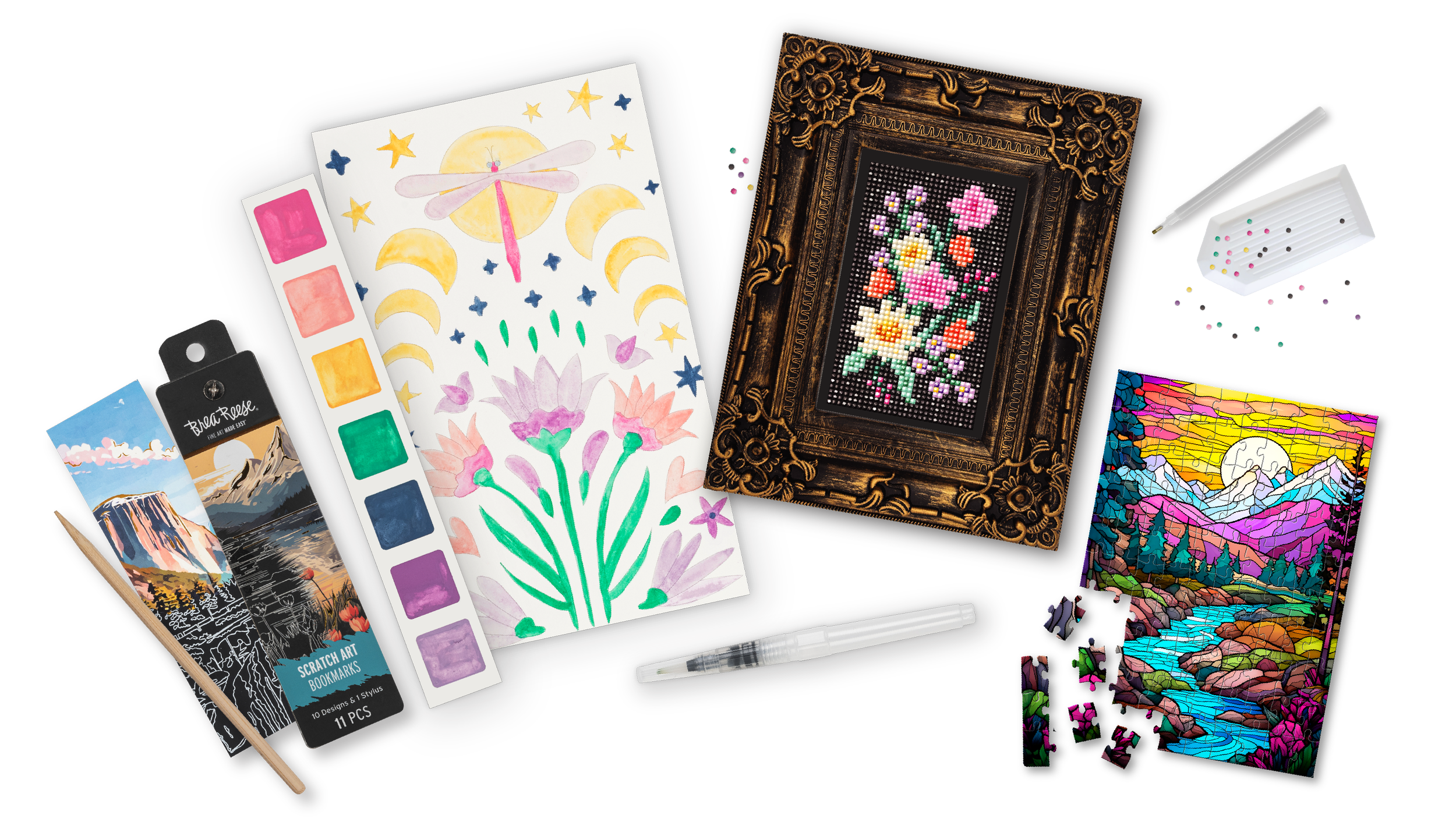 Assorted art supplies and projects including watercolor and acrylic paintings of landscapes, a colorful floral painting, a stained glass mountain scene, a framed pixel art cross-stitch, a scratch art bookmark, a black marker, a white gel pen, a pack of colored pins, and a white box of assorted small pins.