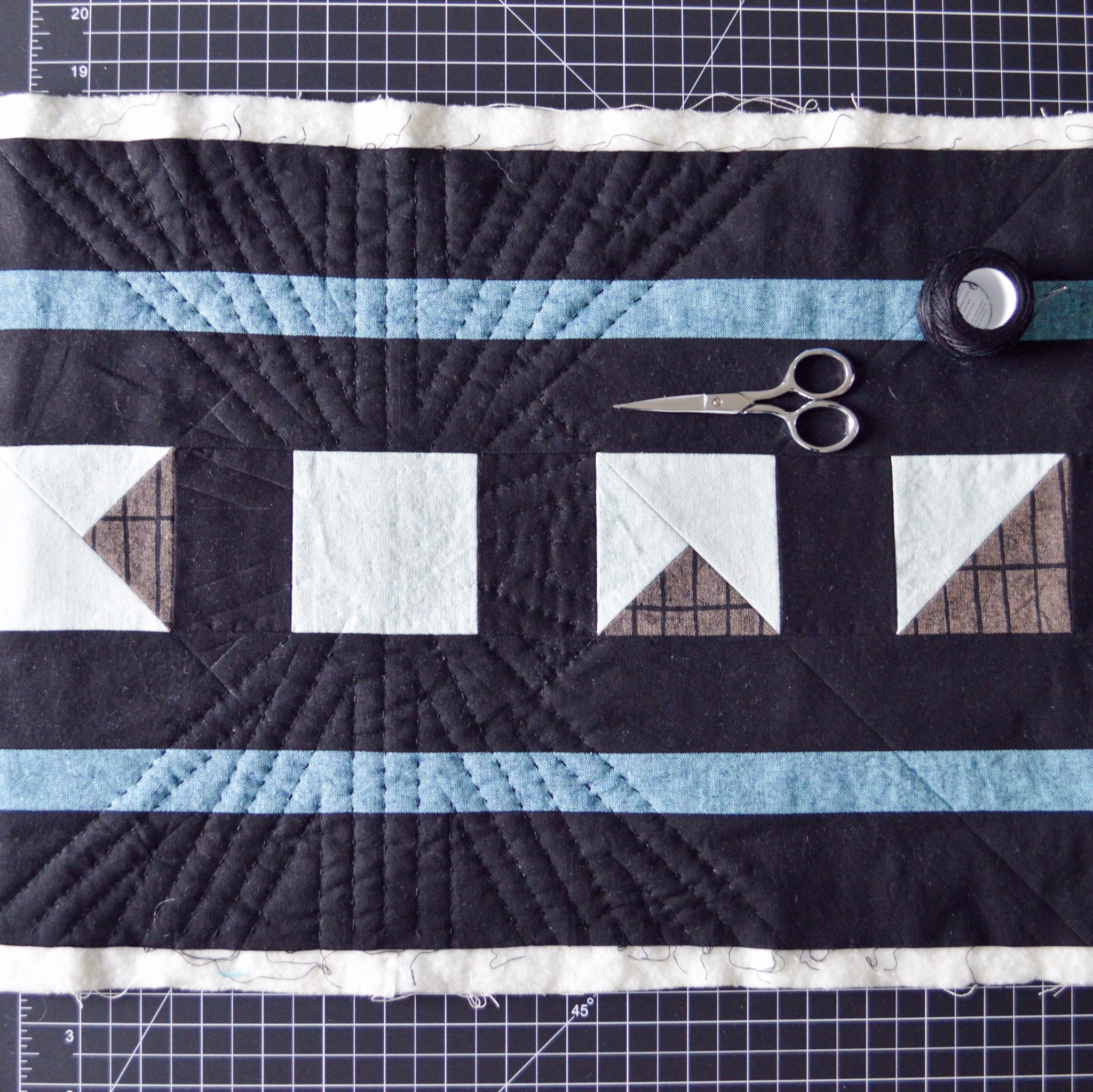  close-up of a hand-quilted mini quilt with black, white and blue fabrics 