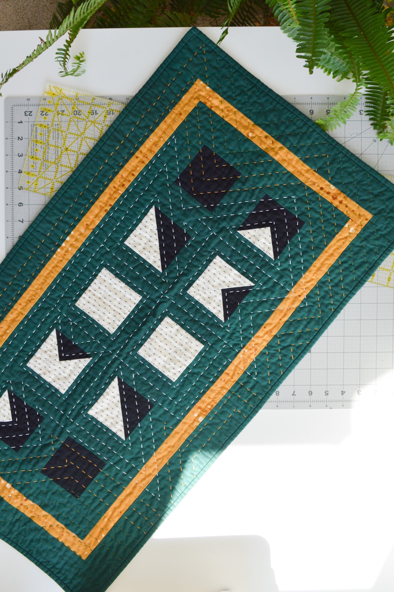  a modern mini quilt on a cutting mat in a sewing room 