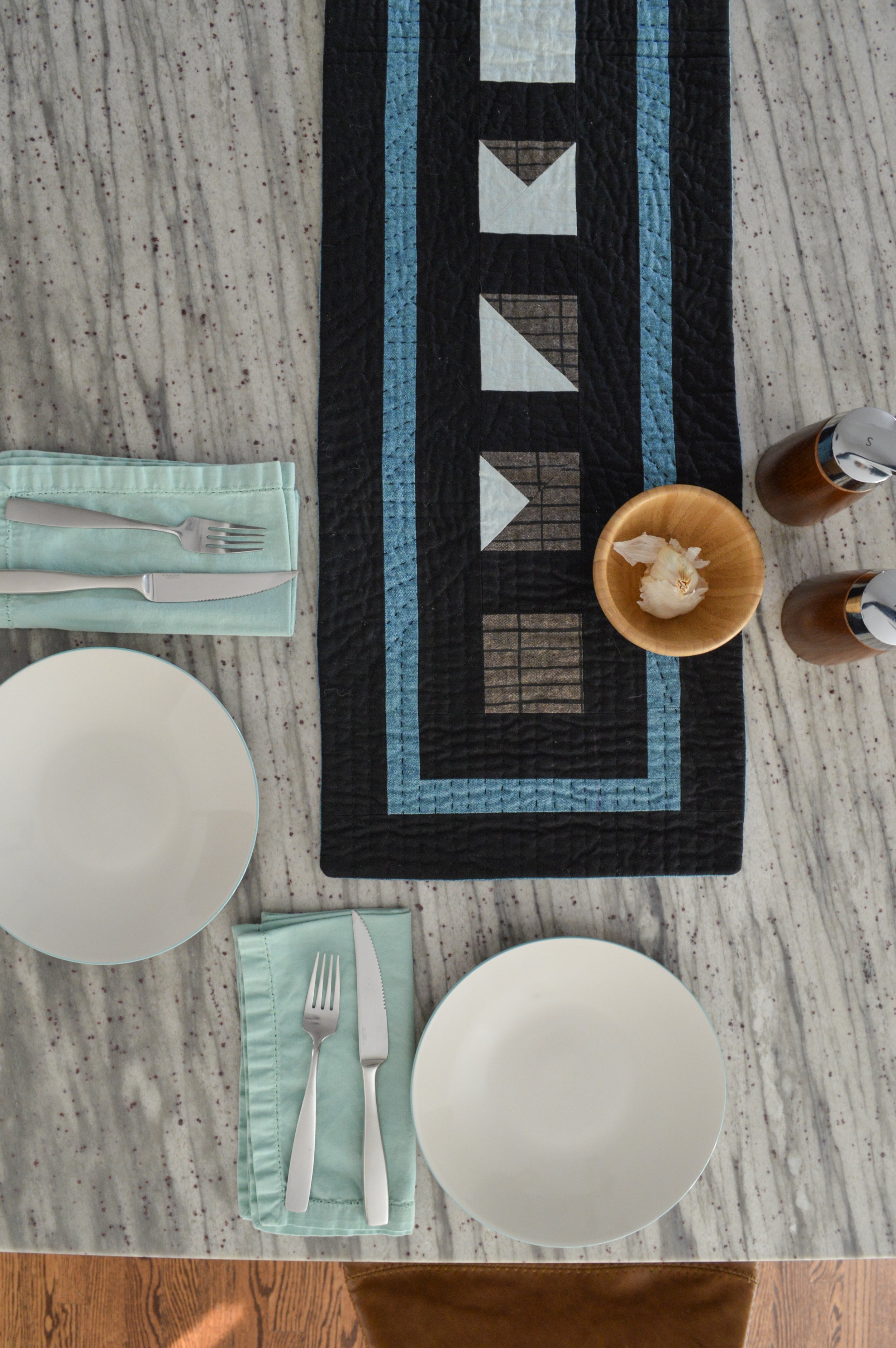  a black, hand-quilted table runner on a granite countertop 