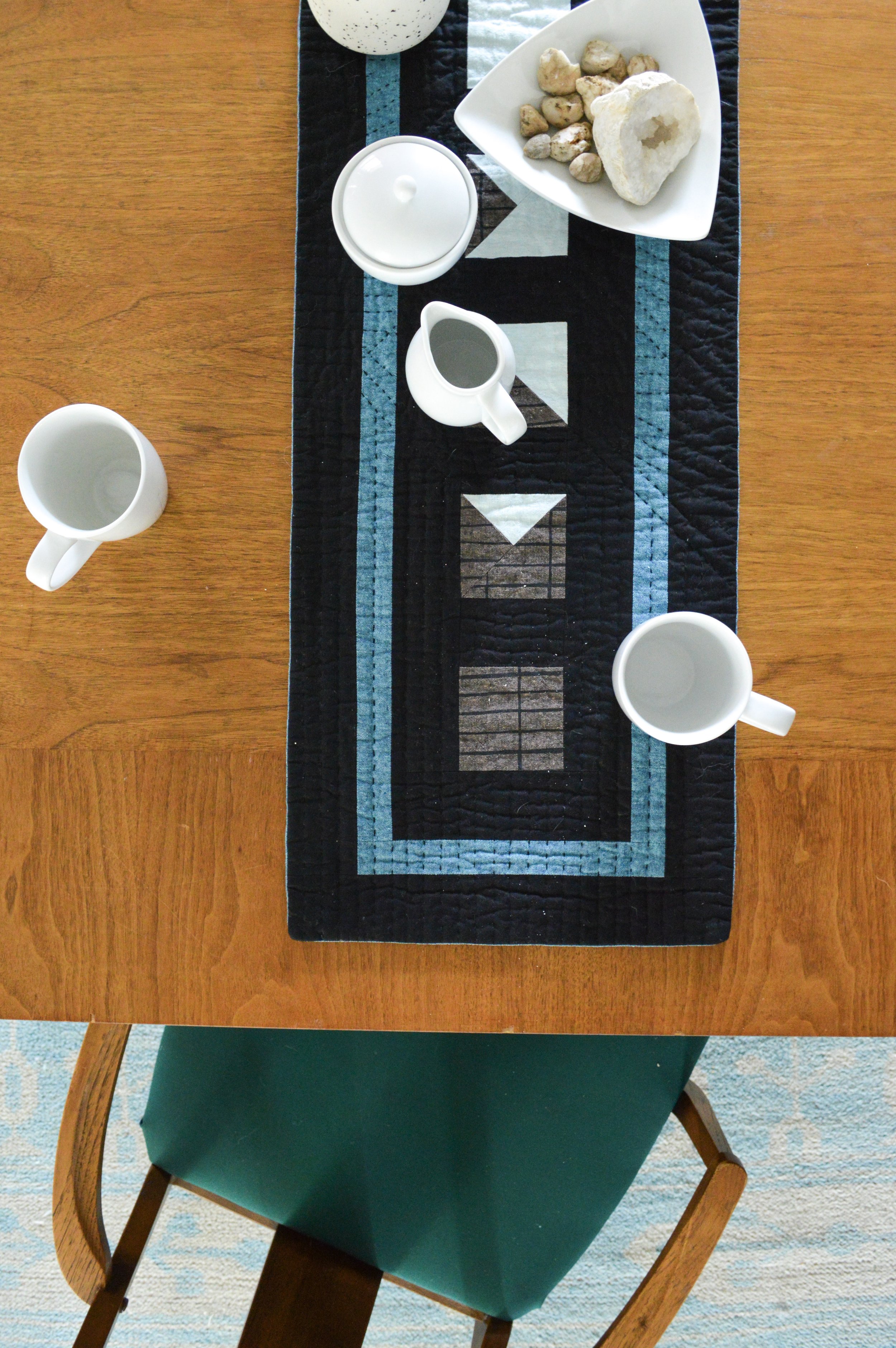  a hand-quilted table runner on a table with setting for tea 