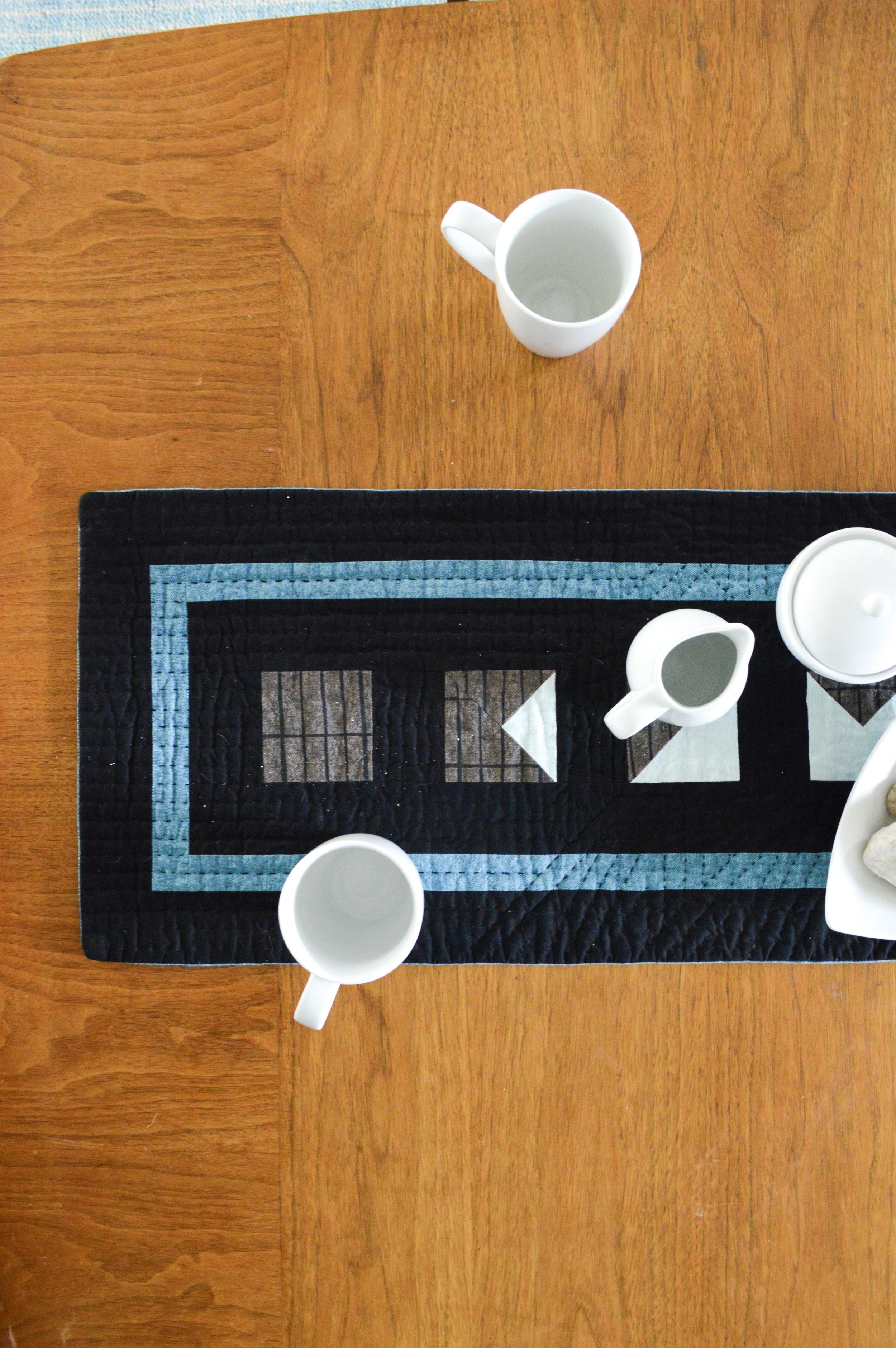  a hand-quilted mini quilt on a table with setting for tea 