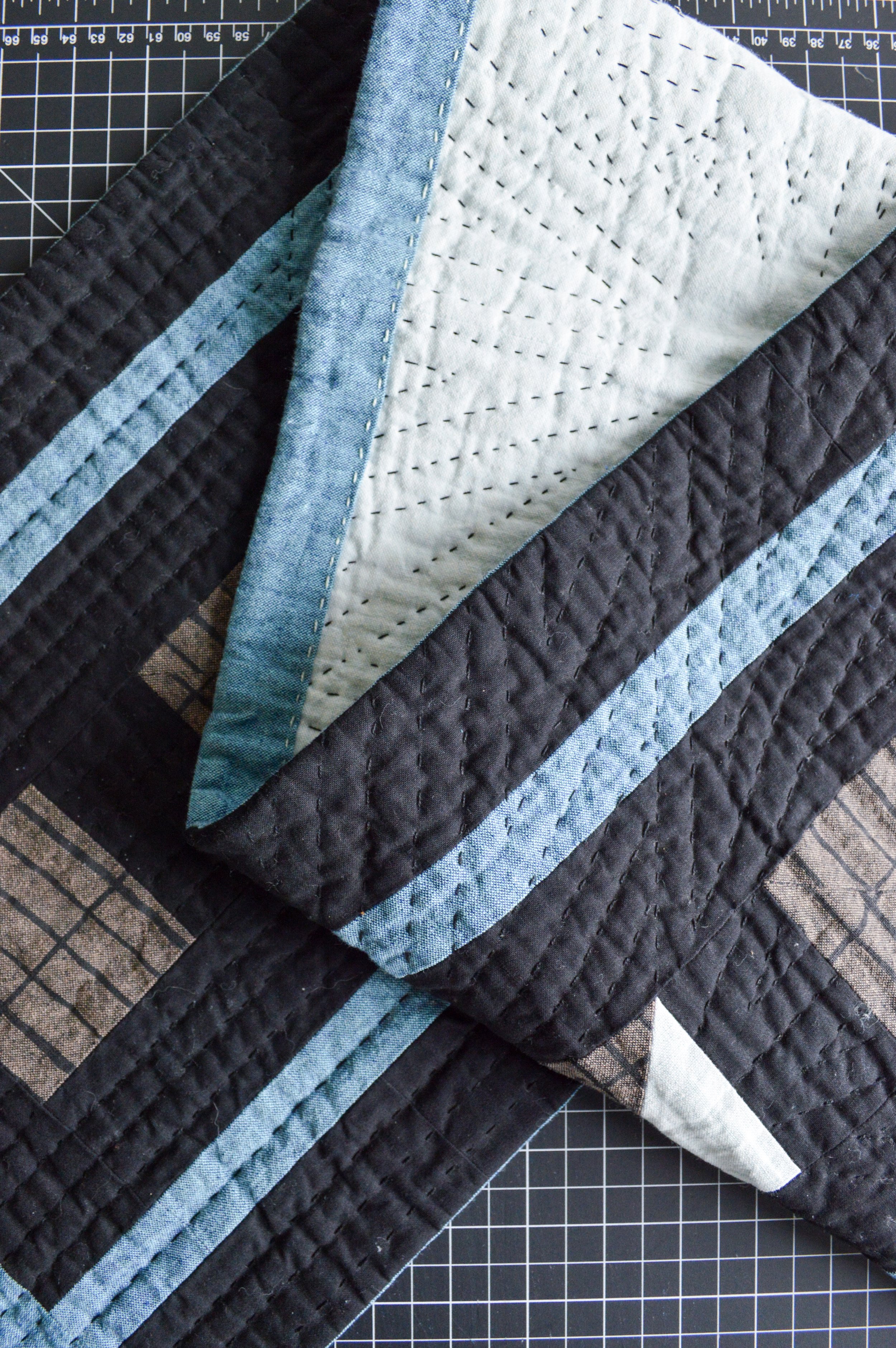  a black, quilted table runner folded up on a black cutting mat 