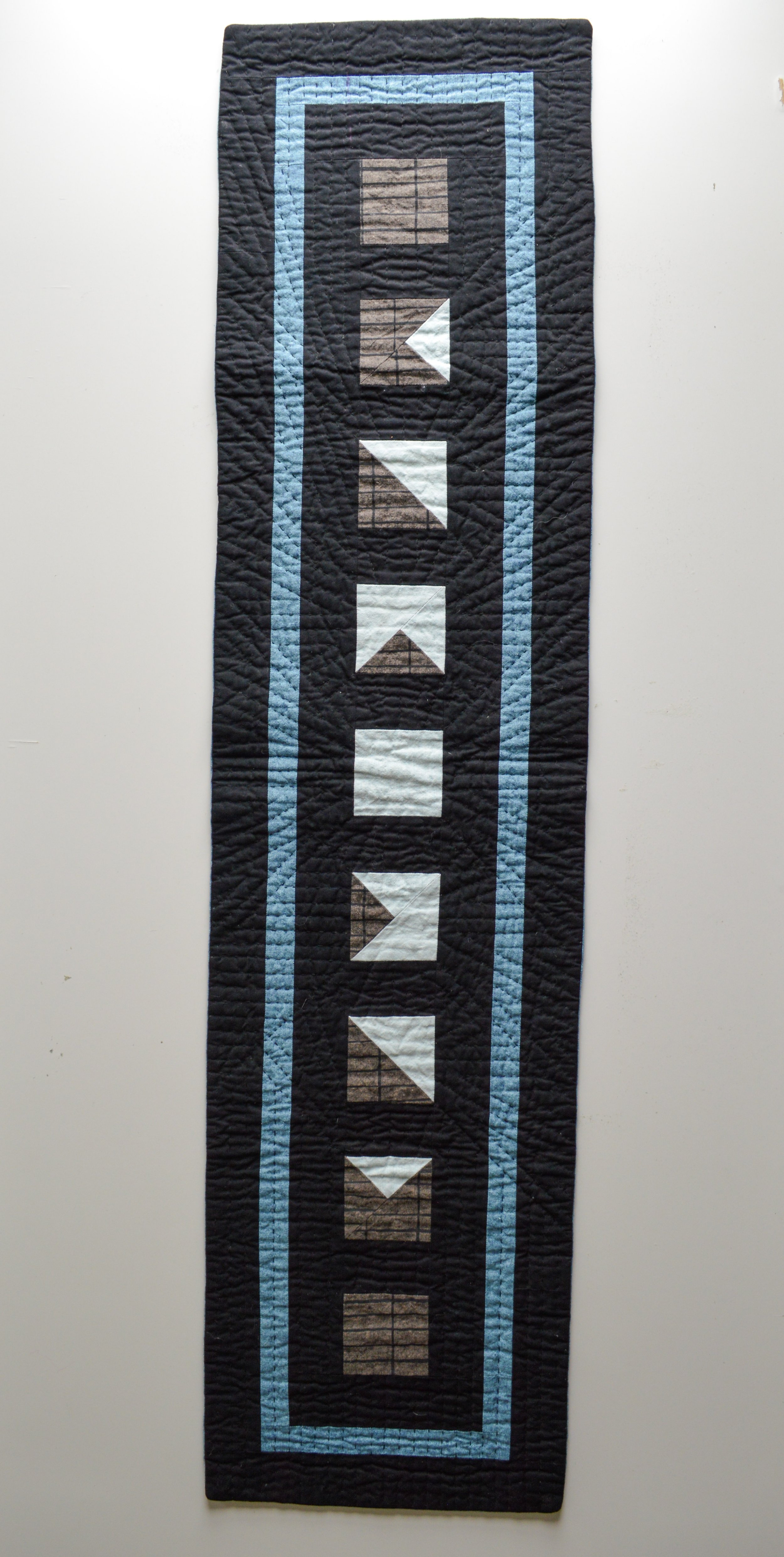  a black mini quilt with a geometric design inspired by the moon 