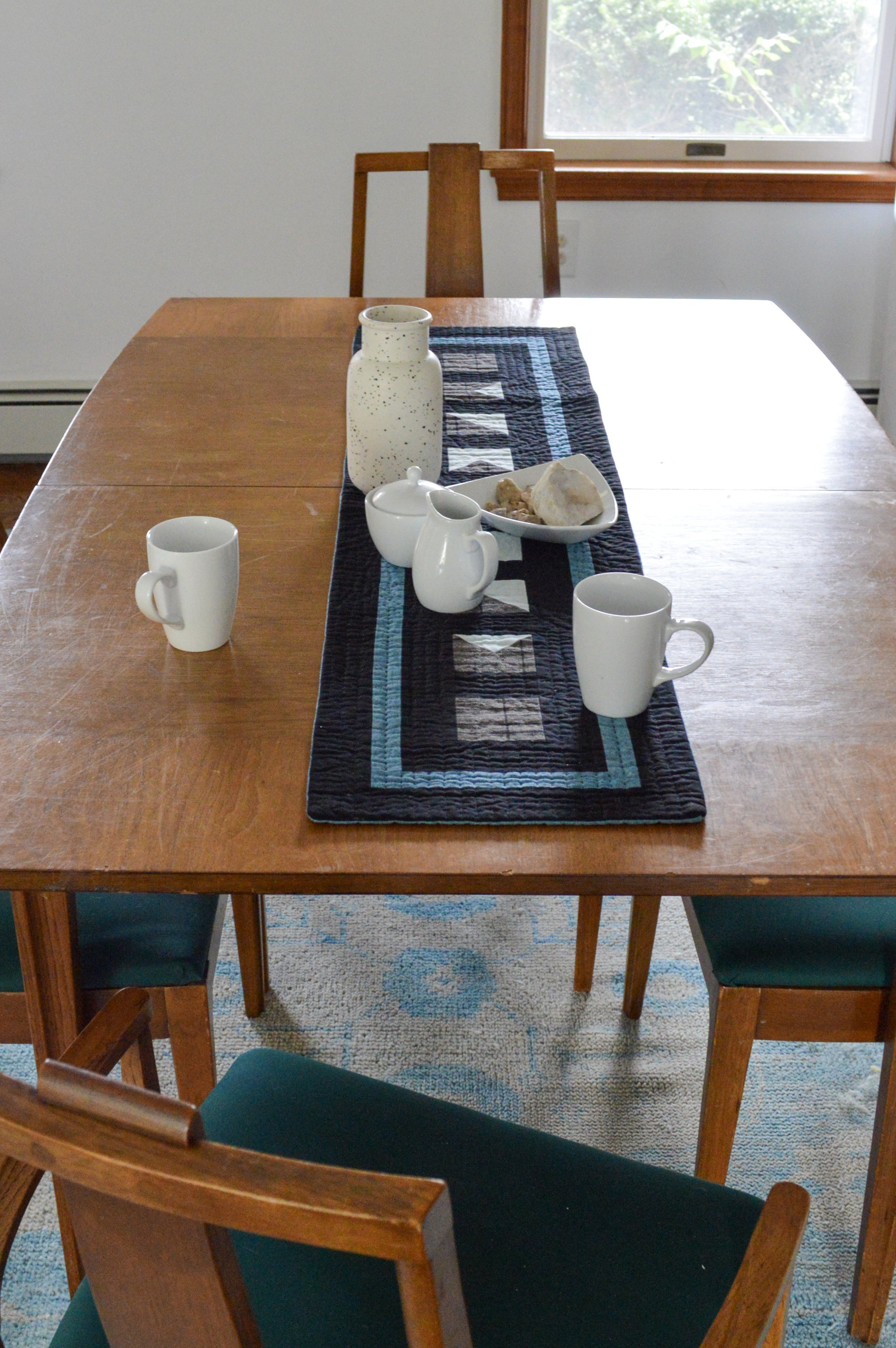  table with setting for tea with a black, quilted, table runner 