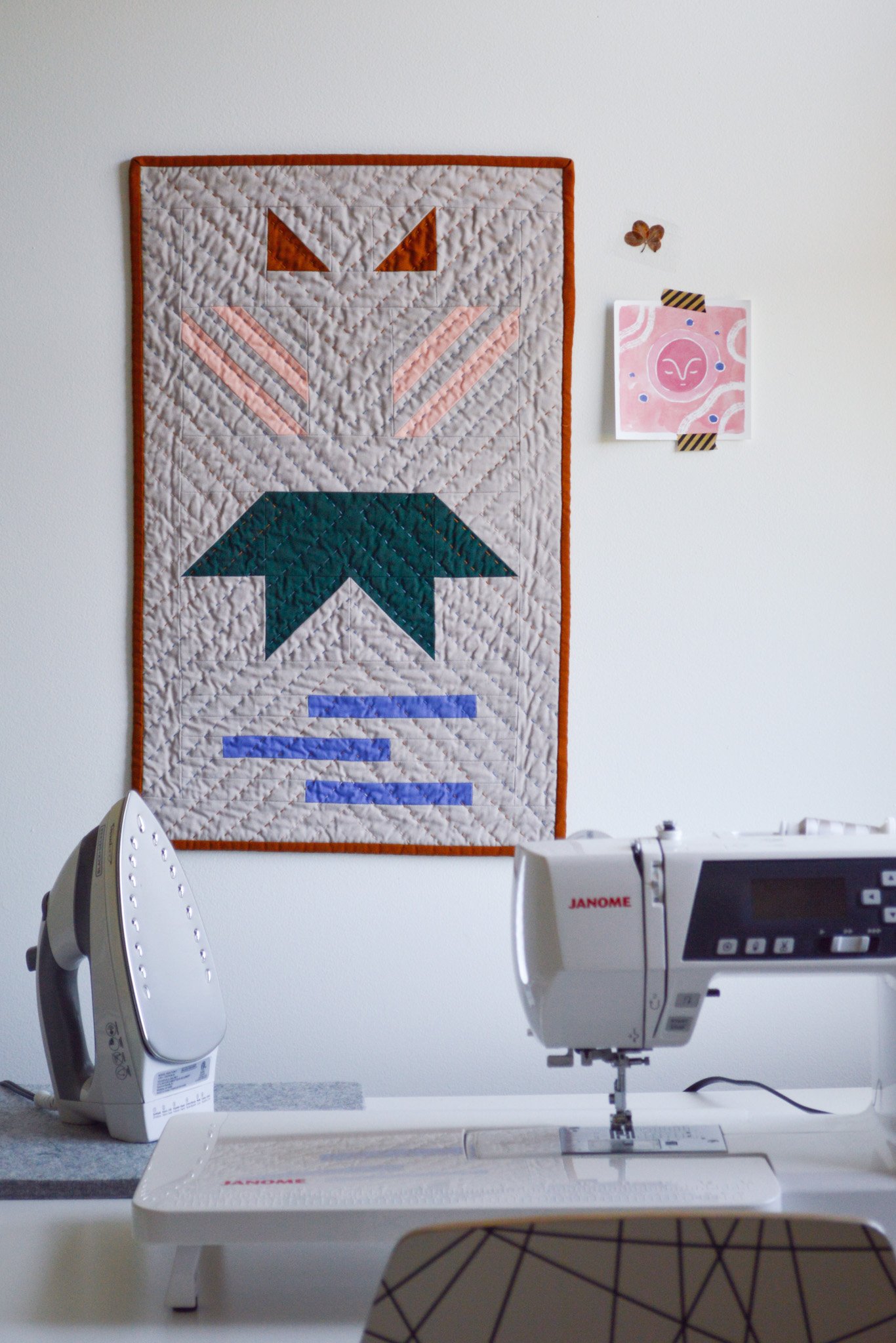  a modern mini quilt hanging on the wall of a sewing studio 