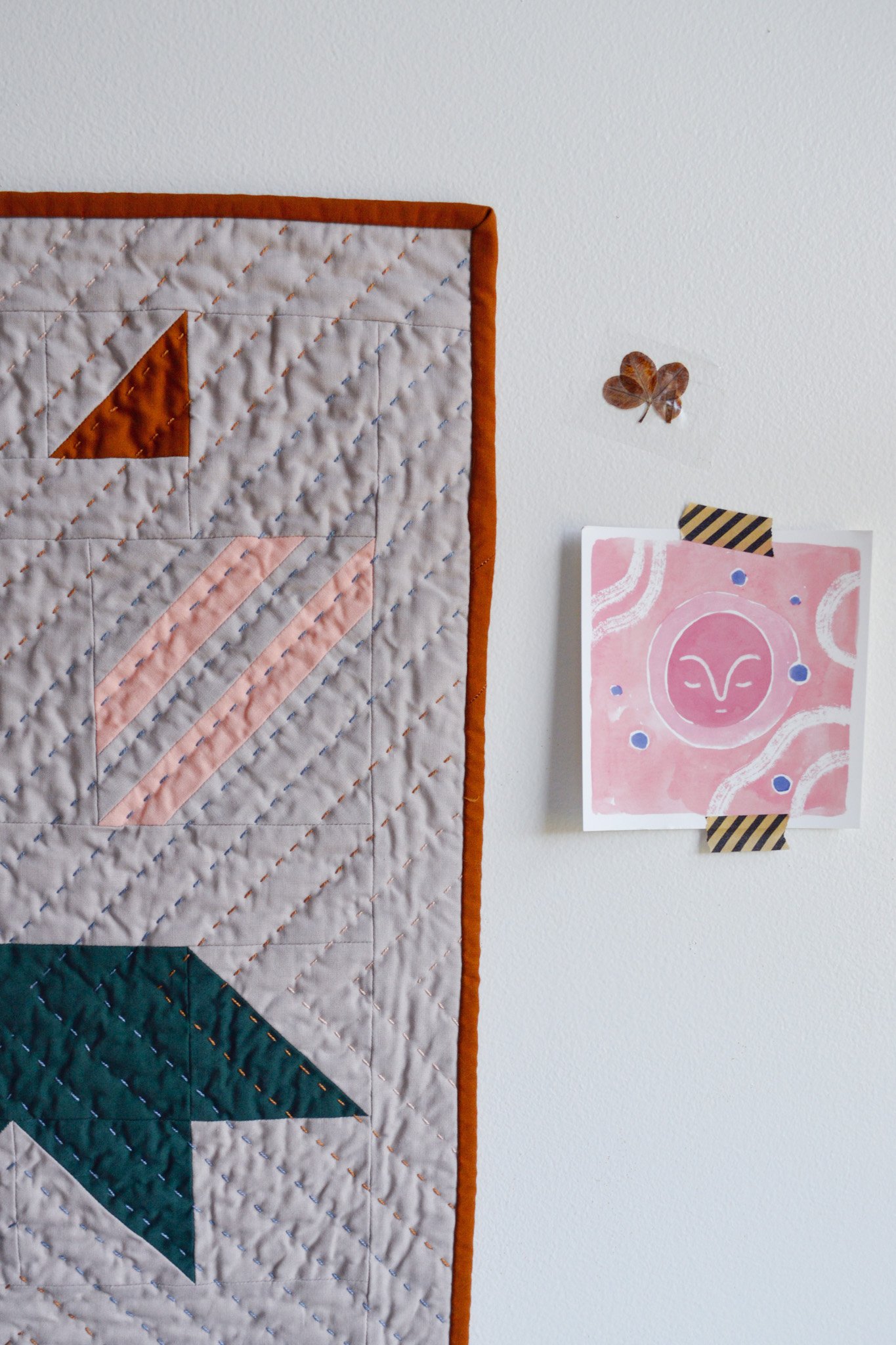  a quilted wall hanging with a modern design hanging on a white wall 