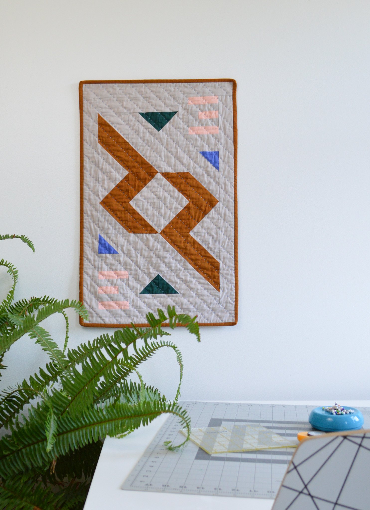  modern mini quilt hanging in a sewing studio 