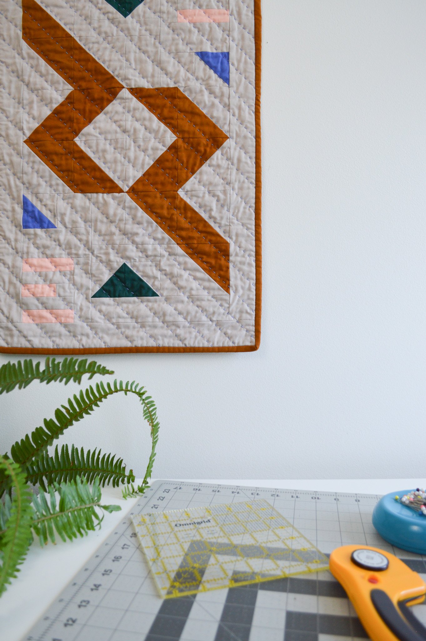  a hand quilted mini quilt hanging in a sewing studio 