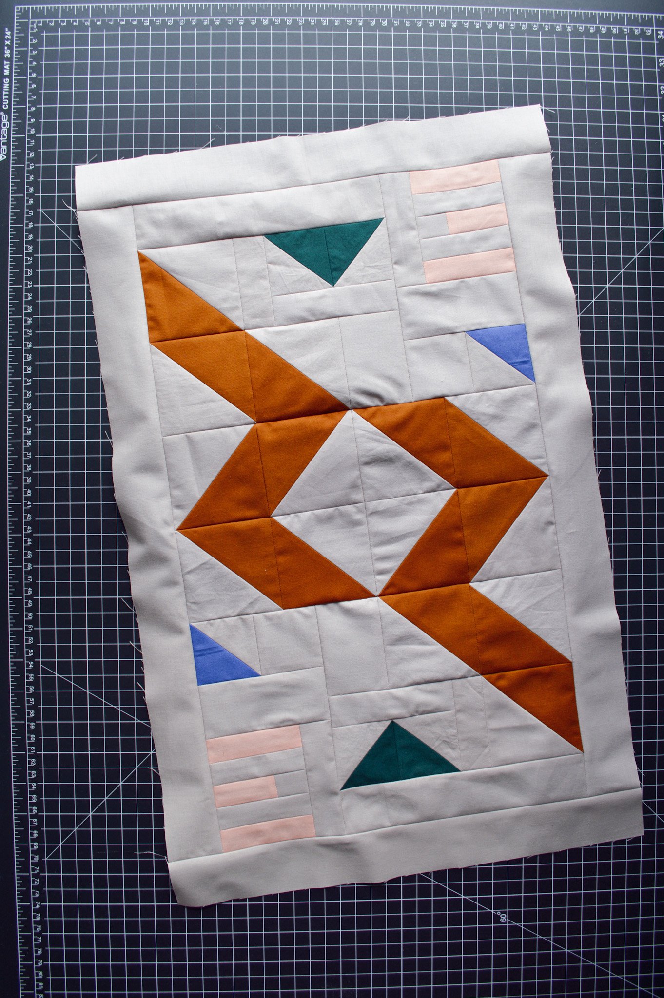  a modern mini quilt top on a black cutting mat 