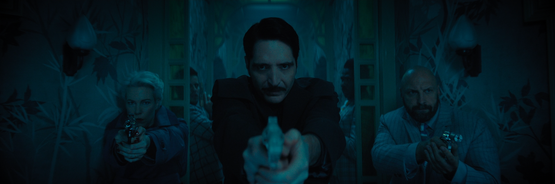 Group of people aiming guns in a dimly lit room with patterned wallpaper and a mirror.