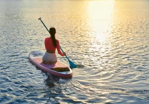 woman paddle boarding with the energy she got from an IV energy cocktail