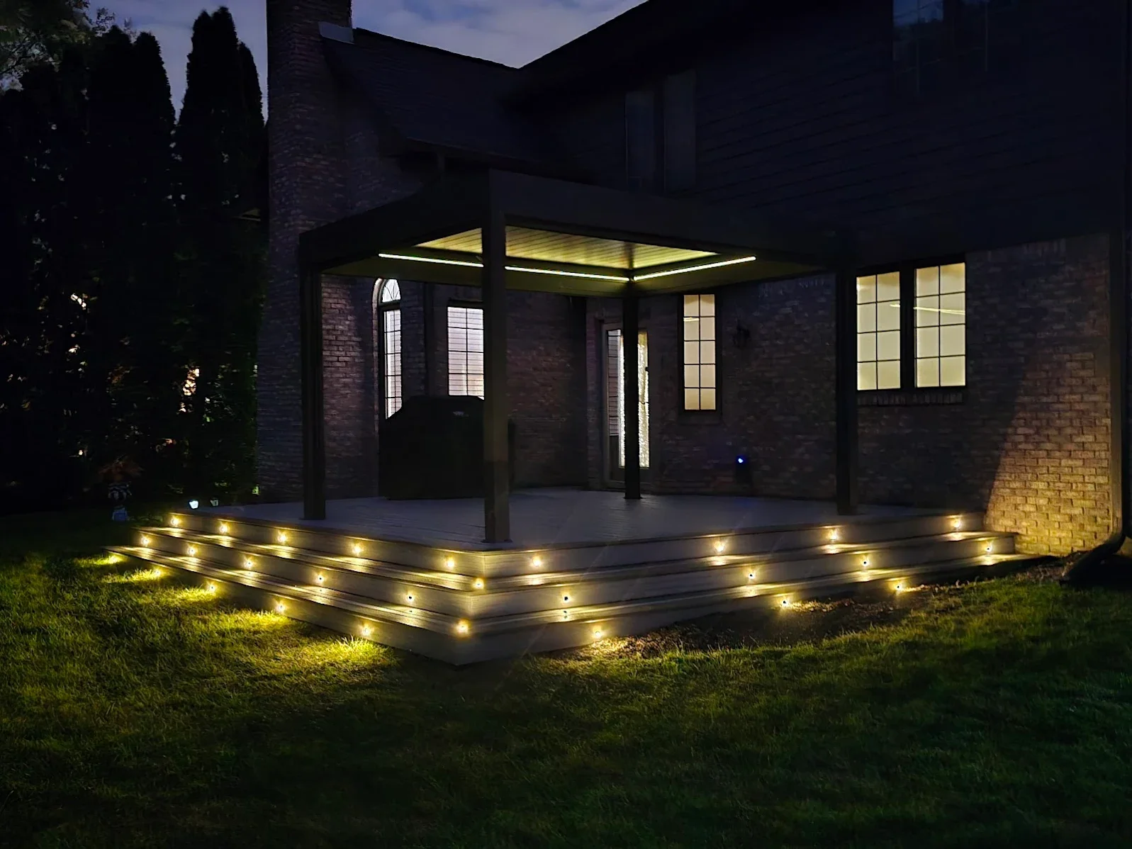 Completed backyard patio renovation in Indianapolis featuring a covered patio, modern pergola, outdoor lighting, and custom hardscape design