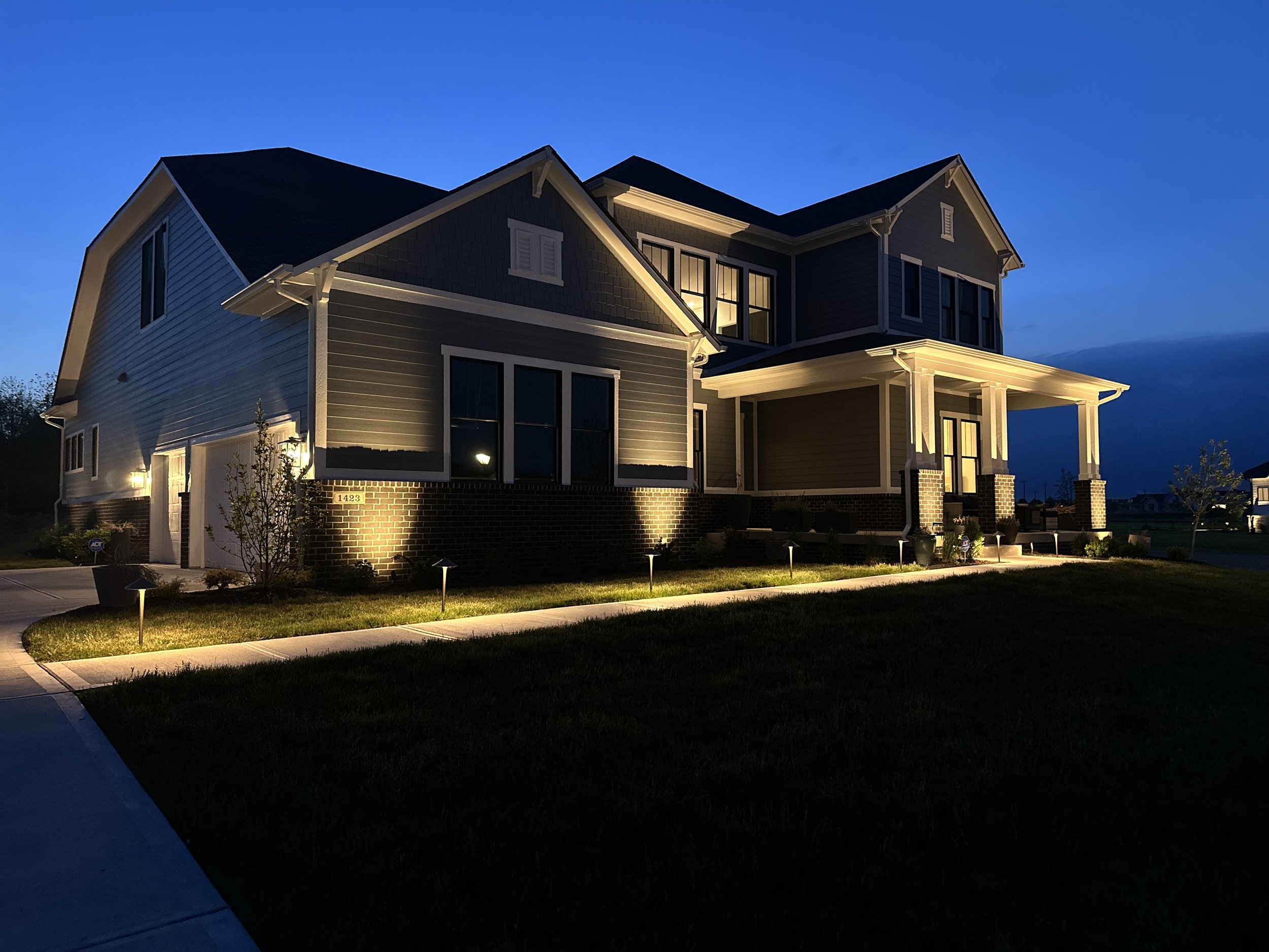 After photo of a custom low-voltage architectural landscape lighting installation by B&F Indianapolis, featuring LED path lights and house uplighting on the front brick facade