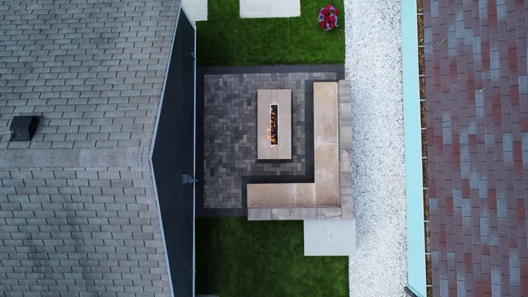 Modern backyard hardscape design with a luxury rectangular gas fire pit and custom stone seating, highlighting professional fire pit and outdoor fireplace installation services.