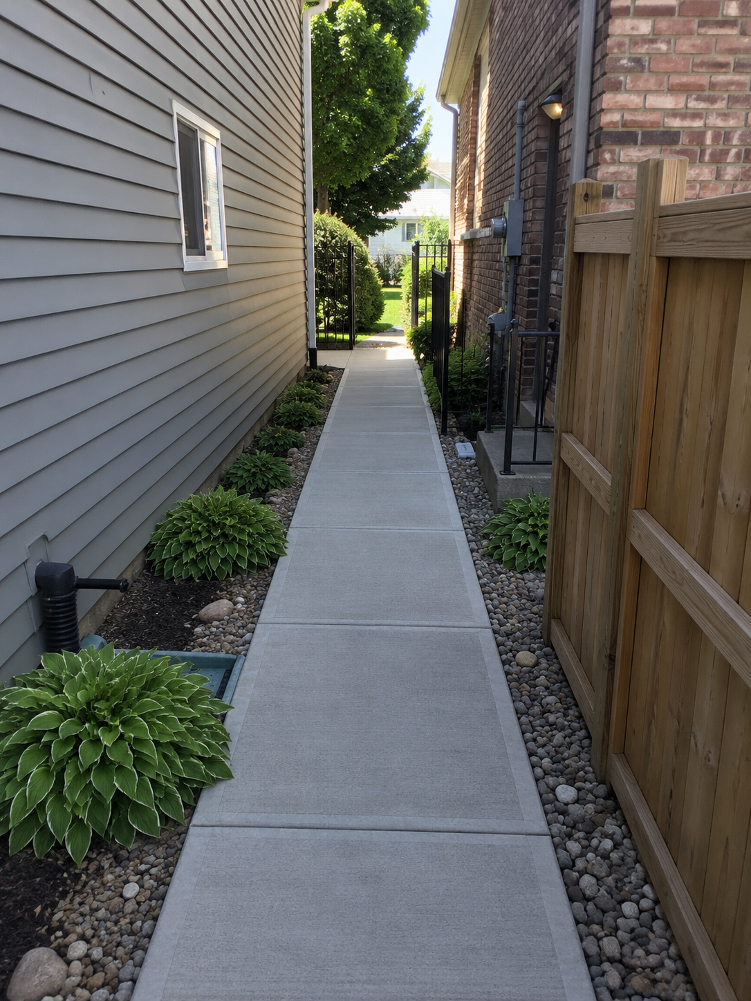 Professionally installed concrete side yard service walk with decorative landscaping and all-weather access in Indianapolis, Indiana.