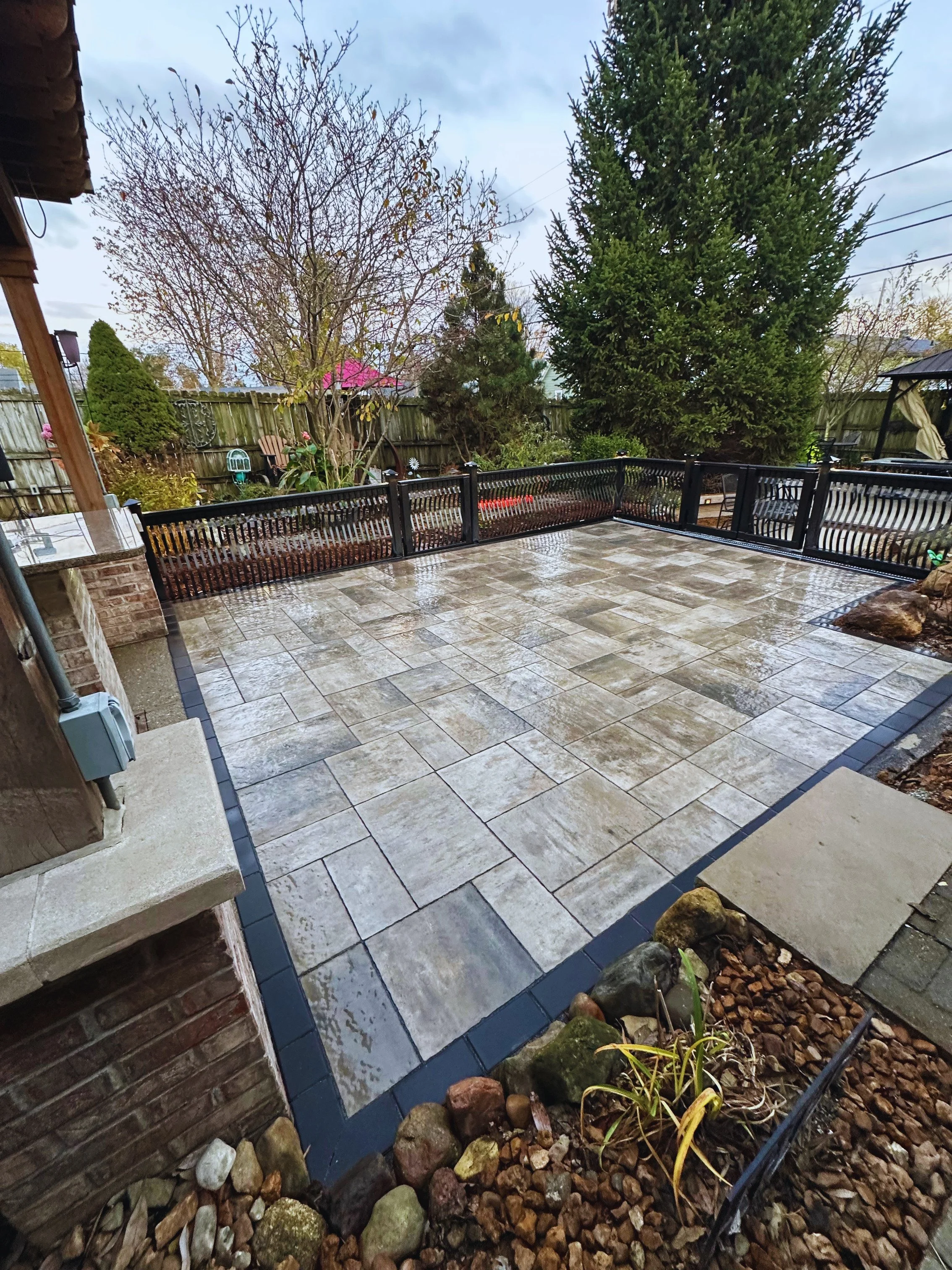Custom paver patio installation by B&F Landscaping in Indianapolis, featuring a modern border design and perimeter fencing.