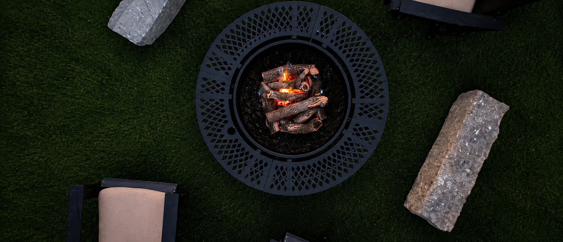 Top-down view of a modern circular metal fire pit surrounded by premium artificial turf and stone seating, installed by B&F Landscaping in Indianapolis.