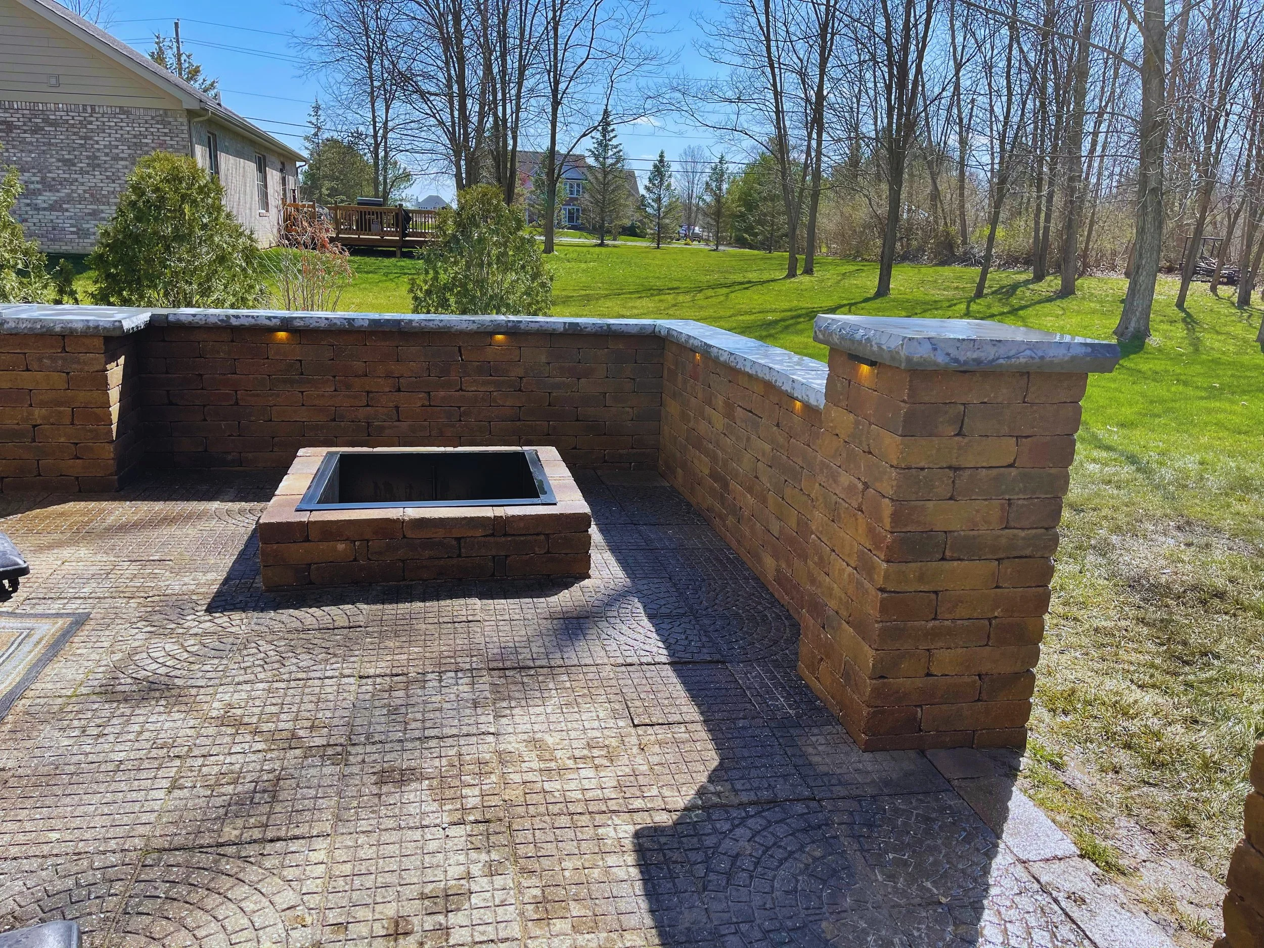 Custom brick paver patio and seating wall with a built-in fire pit, professionally installed by B&F Landscaping in Indianapolis.