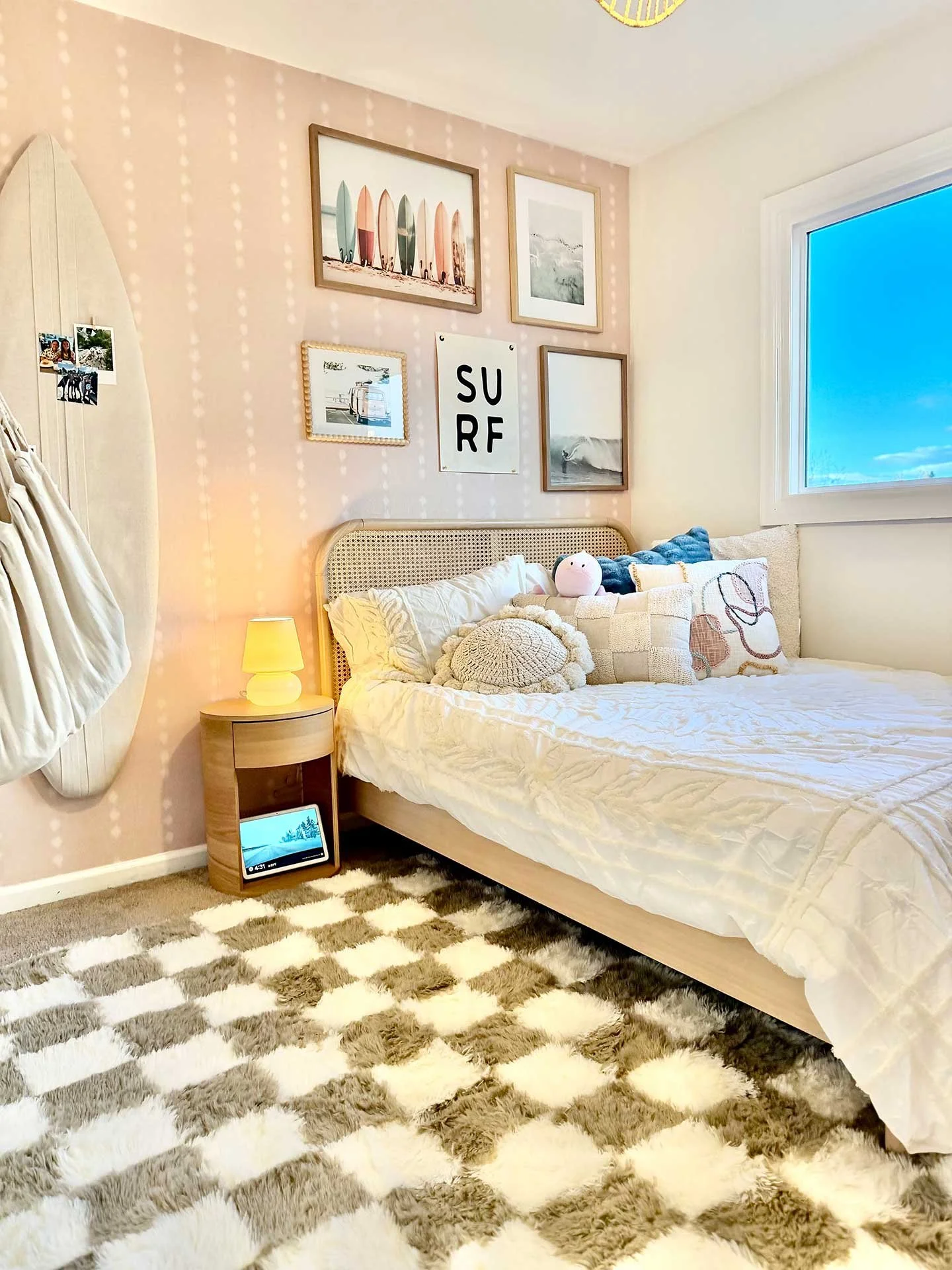 Surf-themed teen bedroom with rattan bed, blush patterned accent wall, beach-inspired gallery art, woven pendant light, and soft layered bedding.